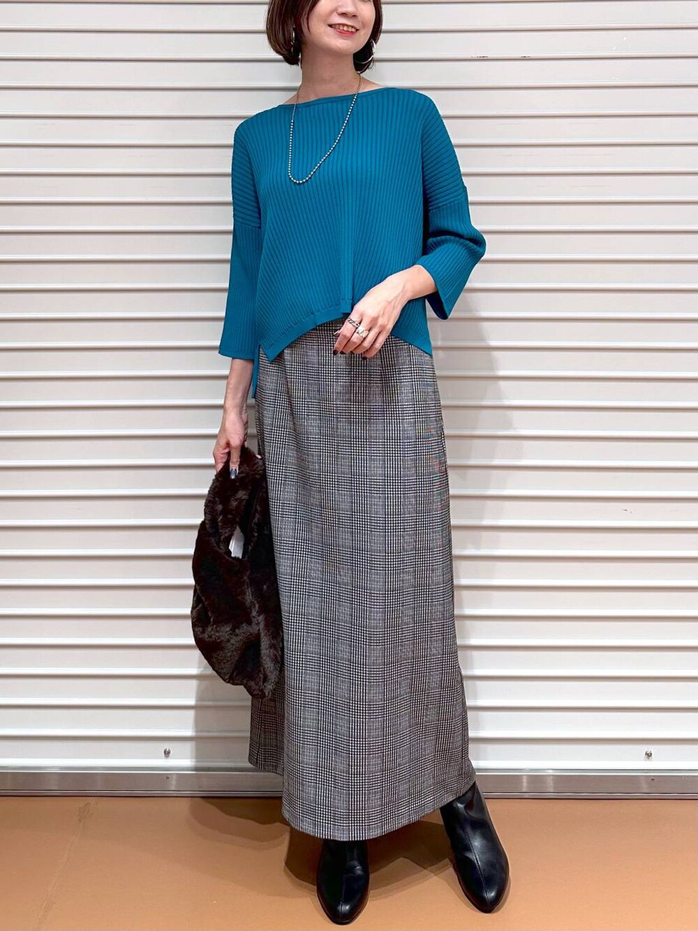 ブラック系のスカート、ブルー系のニット/セーター、シルバー系のネックレスを着用したレディースの秋コーディネートの5枚目の写真