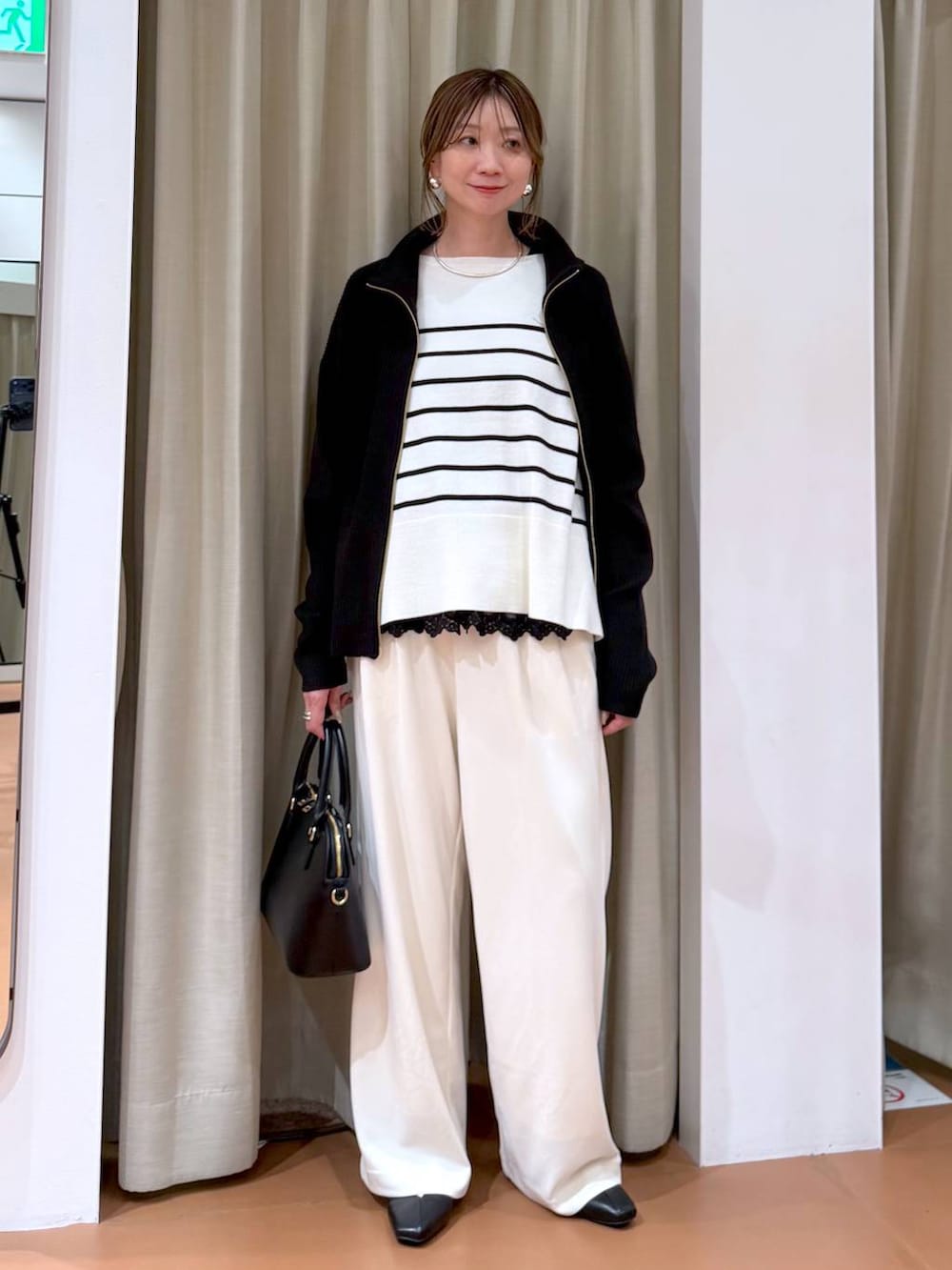 ホワイト系のニット/セーター、ブラック系のカーディガン/ボレロ、ブラック系のハンドバッグを着用したレディースの冬コーディネートの2枚目の写真