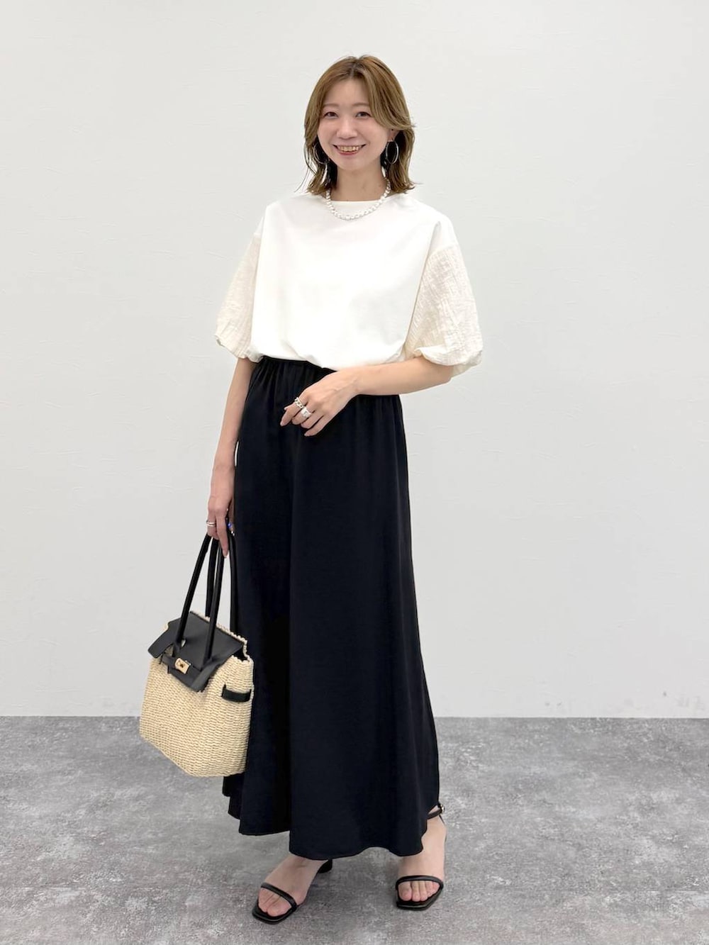 ホワイト系のTシャツ/カットソー、ブラック系のスカート、ゴールド系のネックレスを着用したレディースの春コーディネートの2枚目の写真