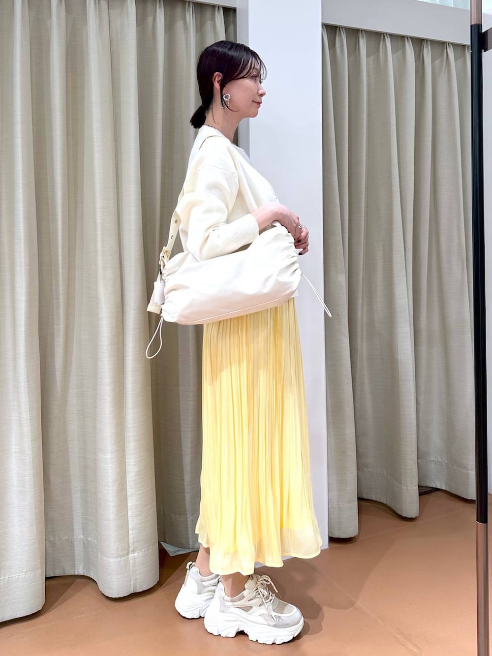 イエロー系のスカート、ホワイト系のカーディガン/ボレロ、ホワイト系のTシャツ/カットソーを着用したレディースの冬コーディネートの5枚目の写真