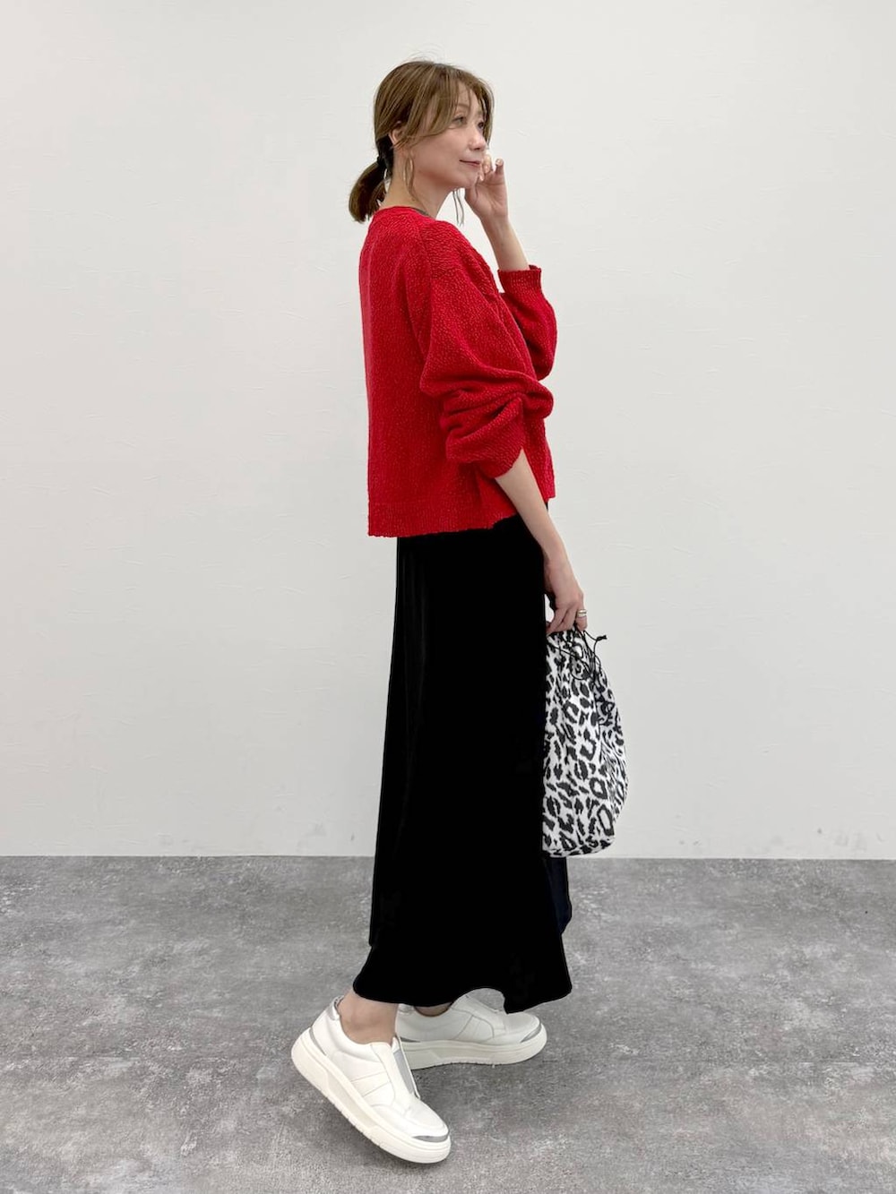 シルバー系のスニーカー、ブラック系のスカート、レッド系のカーディガン/ボレロを着用したレディースの春コーディネートの3枚目の写真