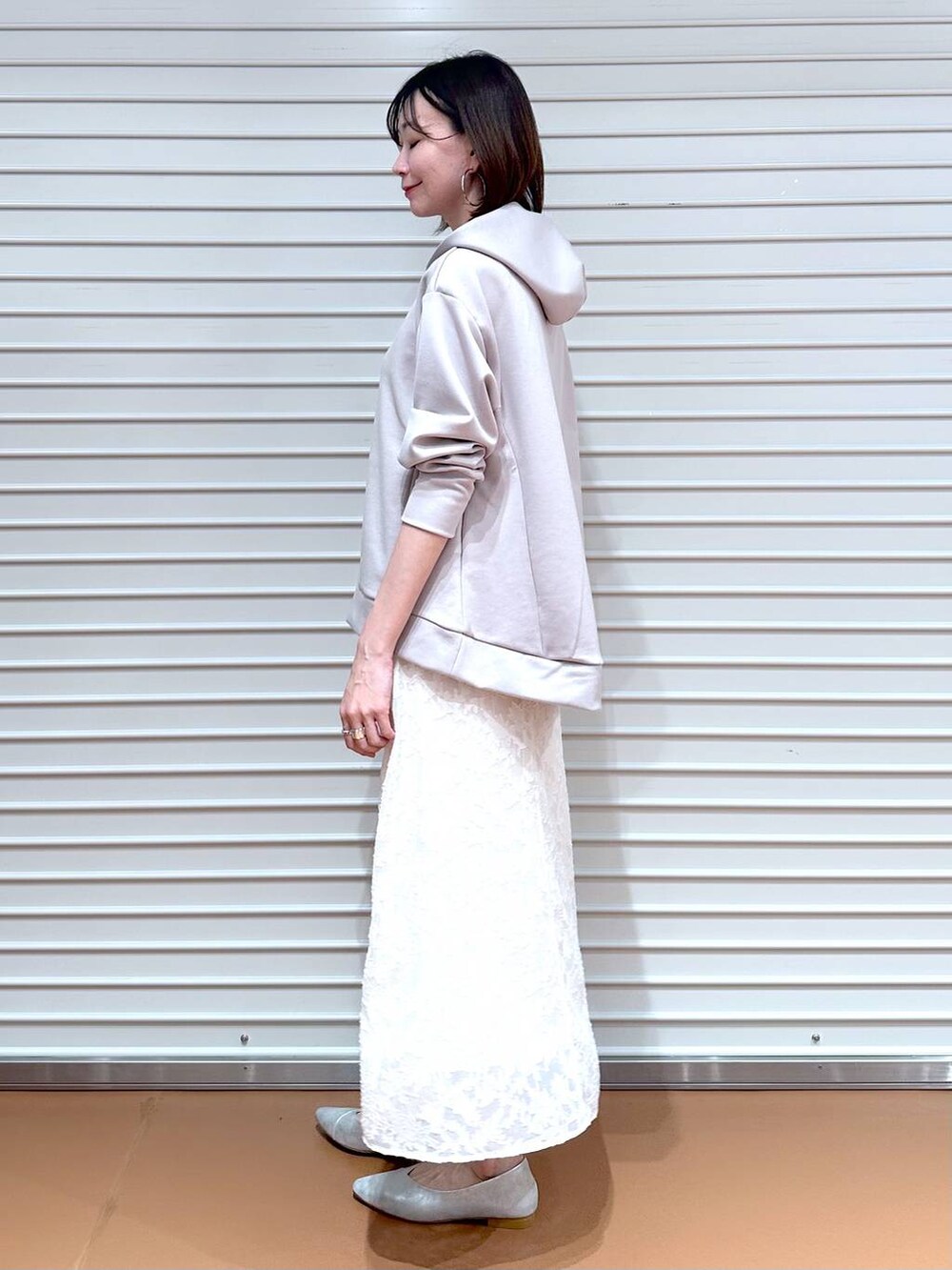 ベージュ系のパーカー、シルバー系のパンプス、ホワイト系のスカートを着用したレディースの春コーディネートの5枚目の写真