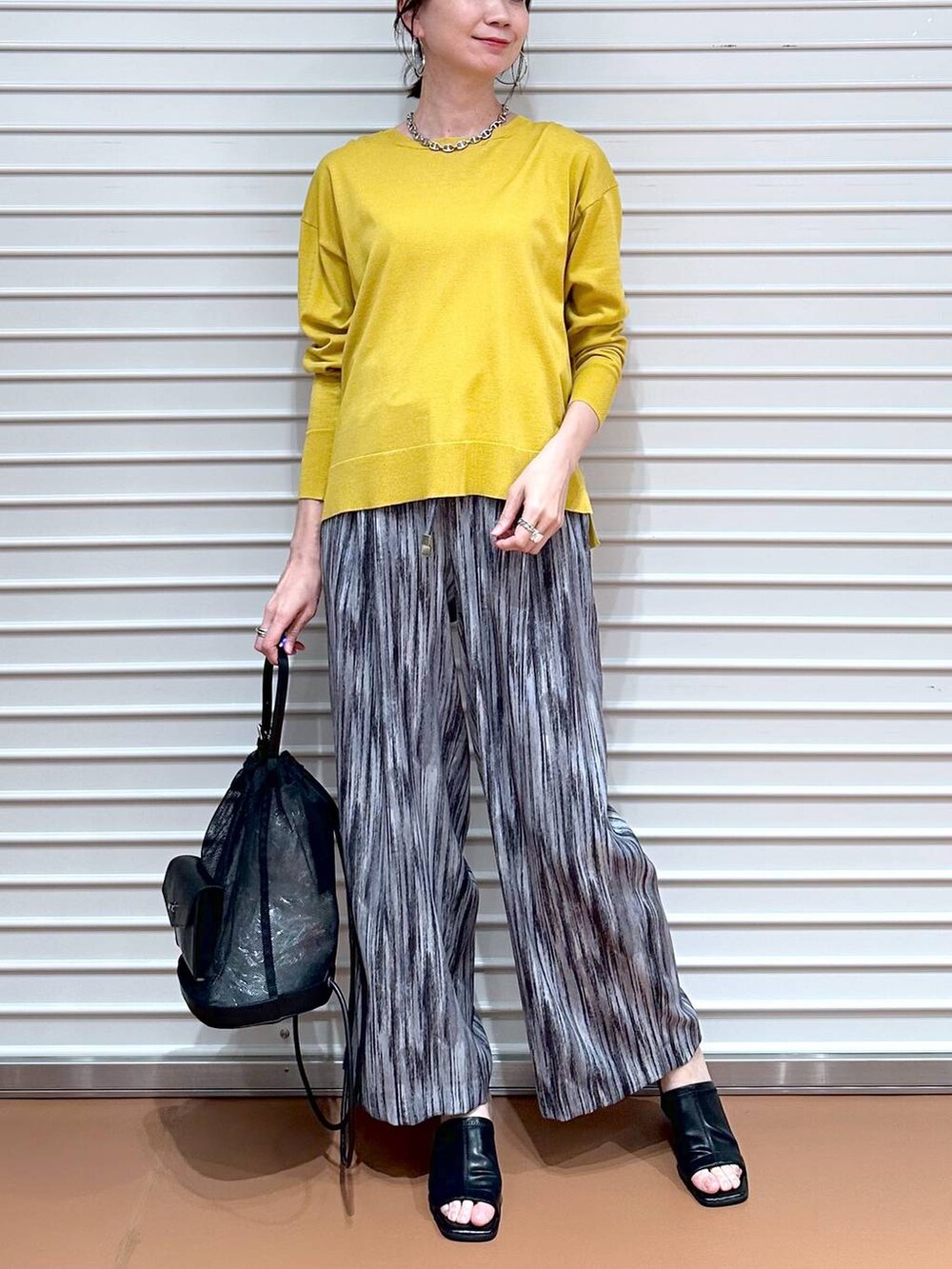 ブラック系のサンダル、グレー系のその他パンツ、イエロー系のニット/セーターを着用したレディースの春コーディネートの5枚目の写真
