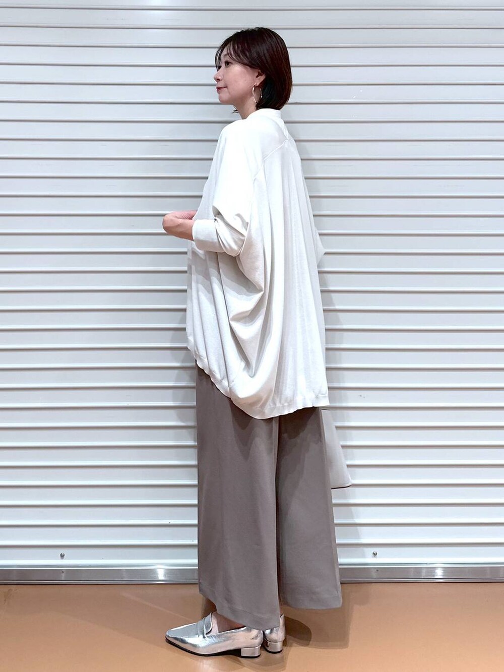 ブラウン系のその他パンツ、グレー系のカーディガン/ボレロ、グレー系のハンドバッグを着用したレディースの秋コーディネートの3枚目の写真