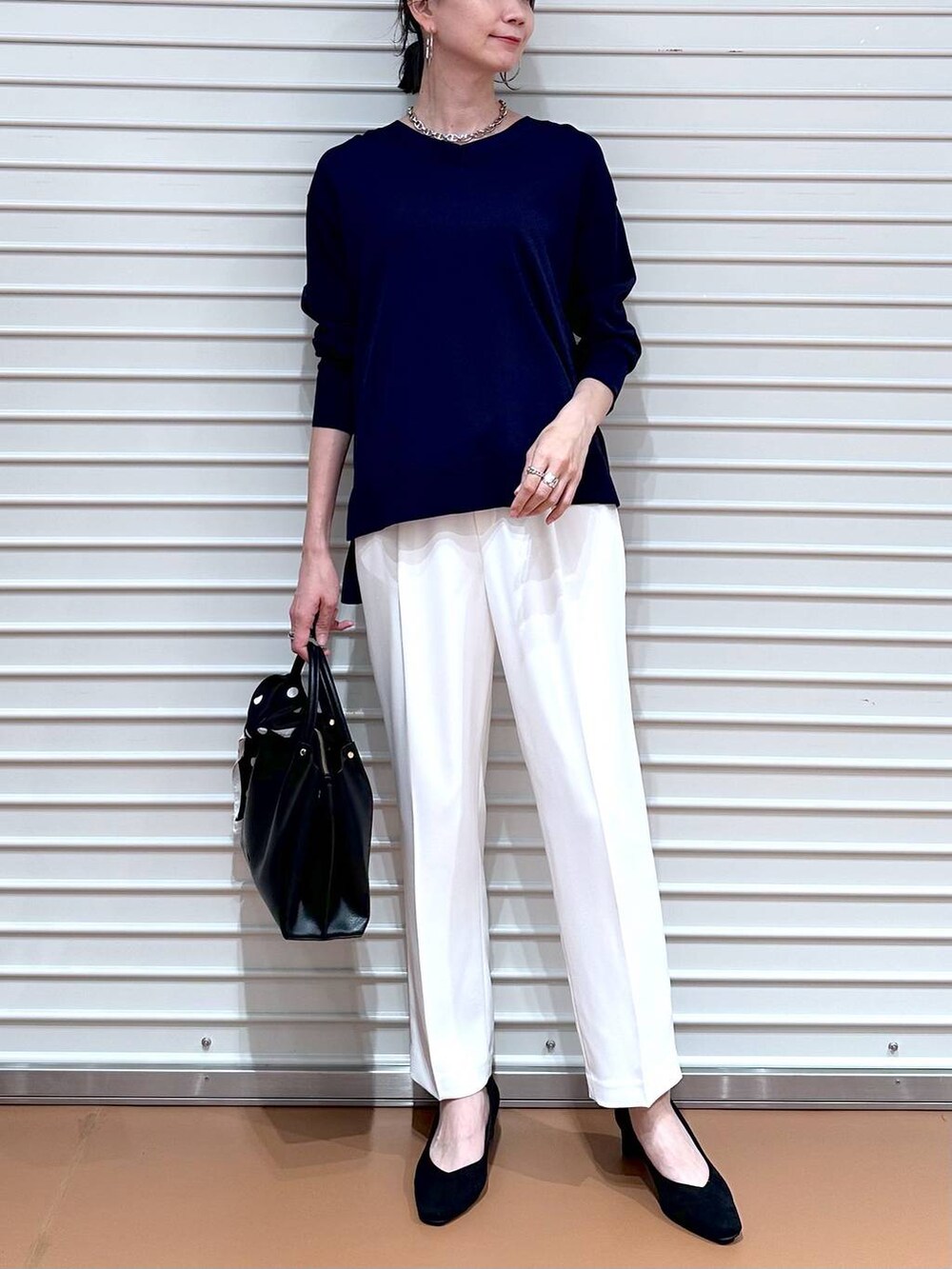 ブルー系のニット/セーター、ブラック系のショルダーバッグ、ホワイト系のその他パンツを着用したレディースの春コーディネートの6枚目の写真