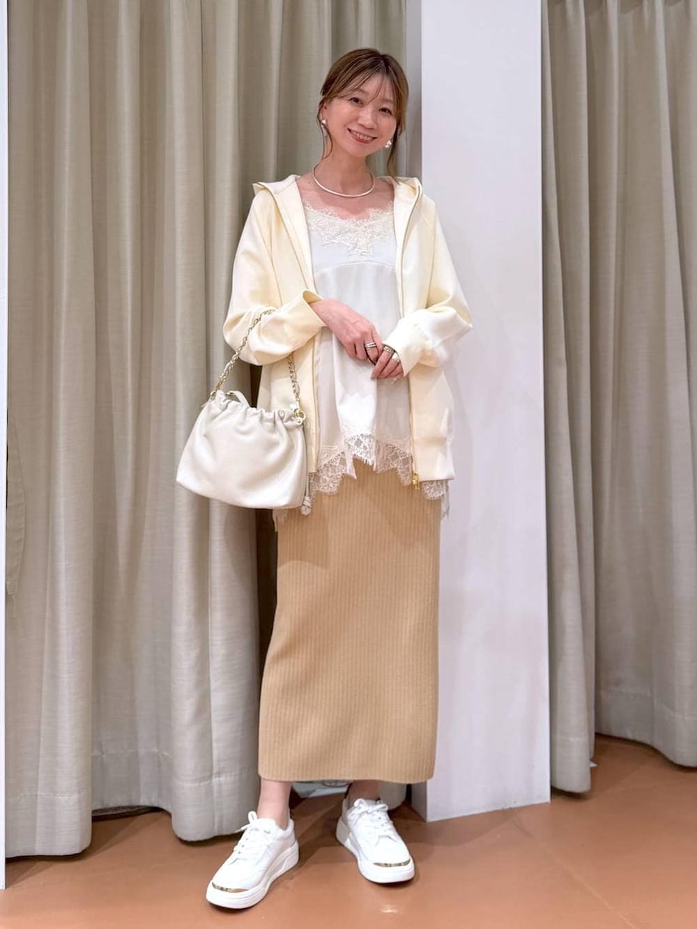 ホワイト系のハンドバッグ、ベージュ系のスカート、ホワイト系のパーカーを着用したレディースの冬コーディネートの2枚目の写真