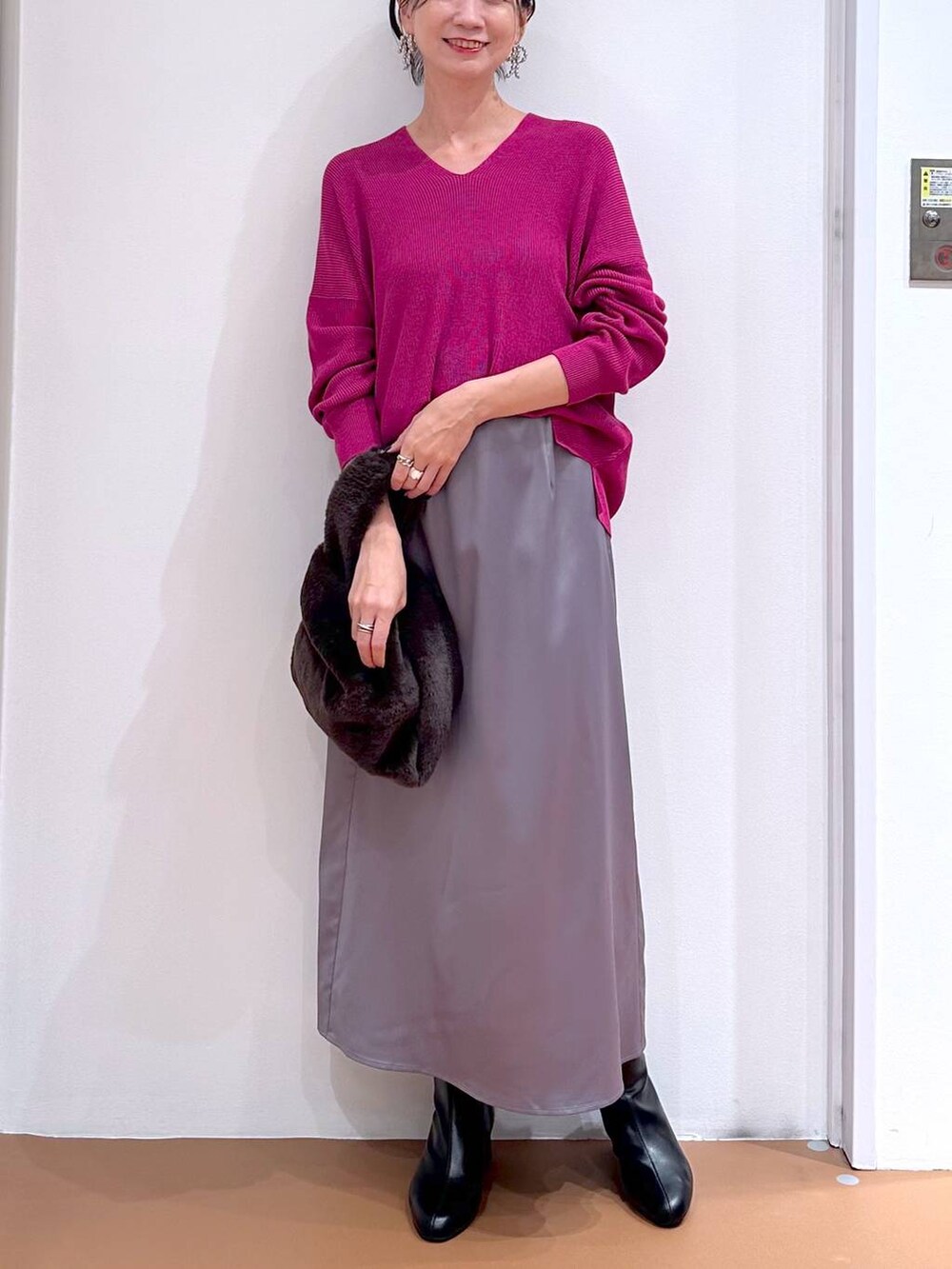 ピンク系のニット/セーター、グレー系のスカート、ブラック系のブーツを着用したレディースの秋コーディネートの5枚目の写真