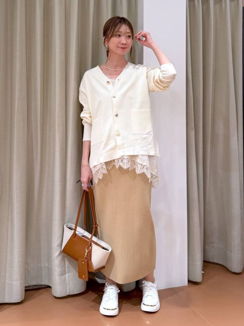 ホワイト系のカーディガン/ボレロ、ベージュ系のスカート、ホワイト系のキャミソールを着用したレディースの冬コーディネートの2枚目の写真