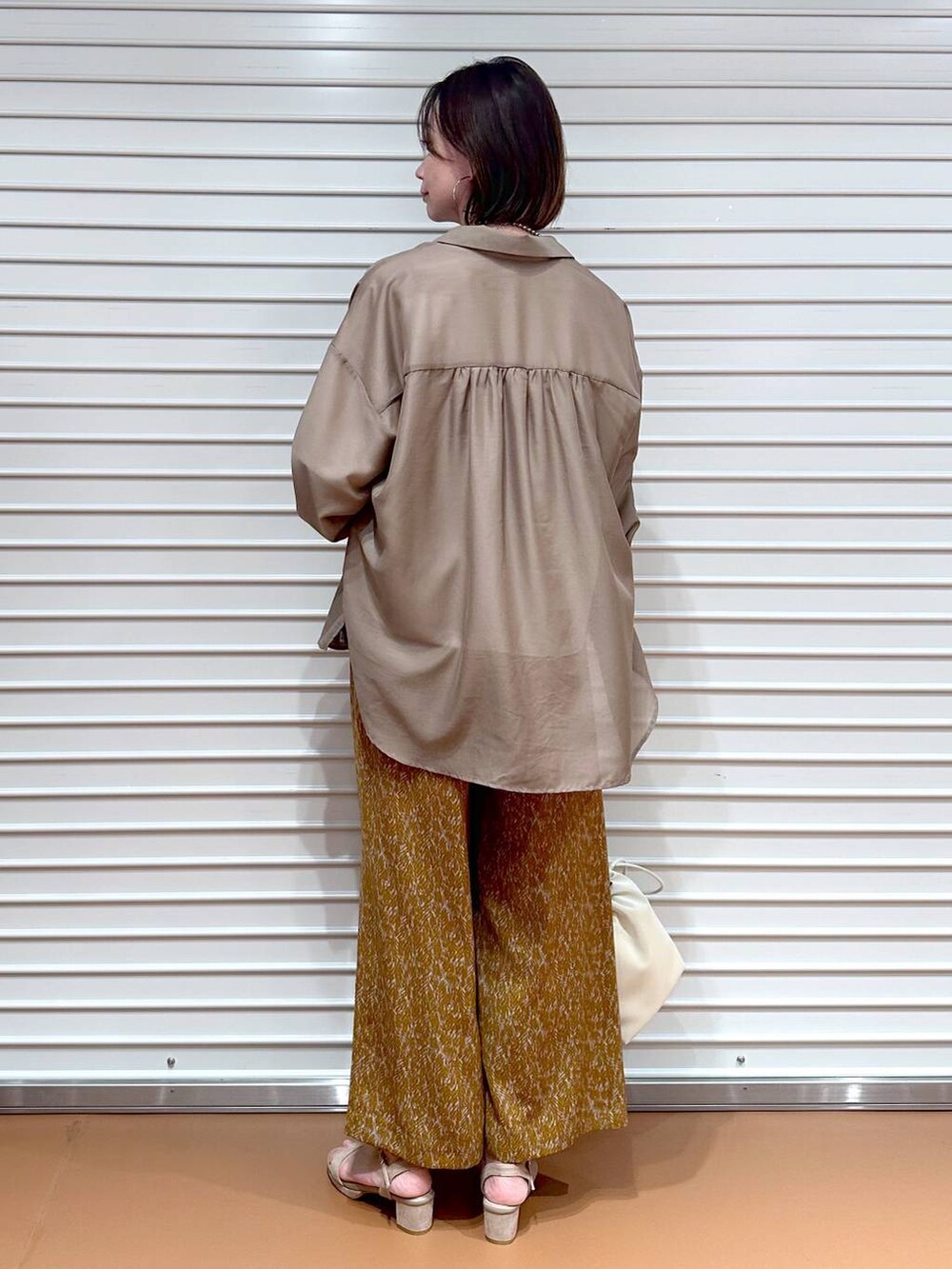 ベージュ系のサンダル、ブラウン系のその他パンツ、ホワイト系のTシャツ/カットソーを着用したレディースの秋コーディネートの4枚目の写真