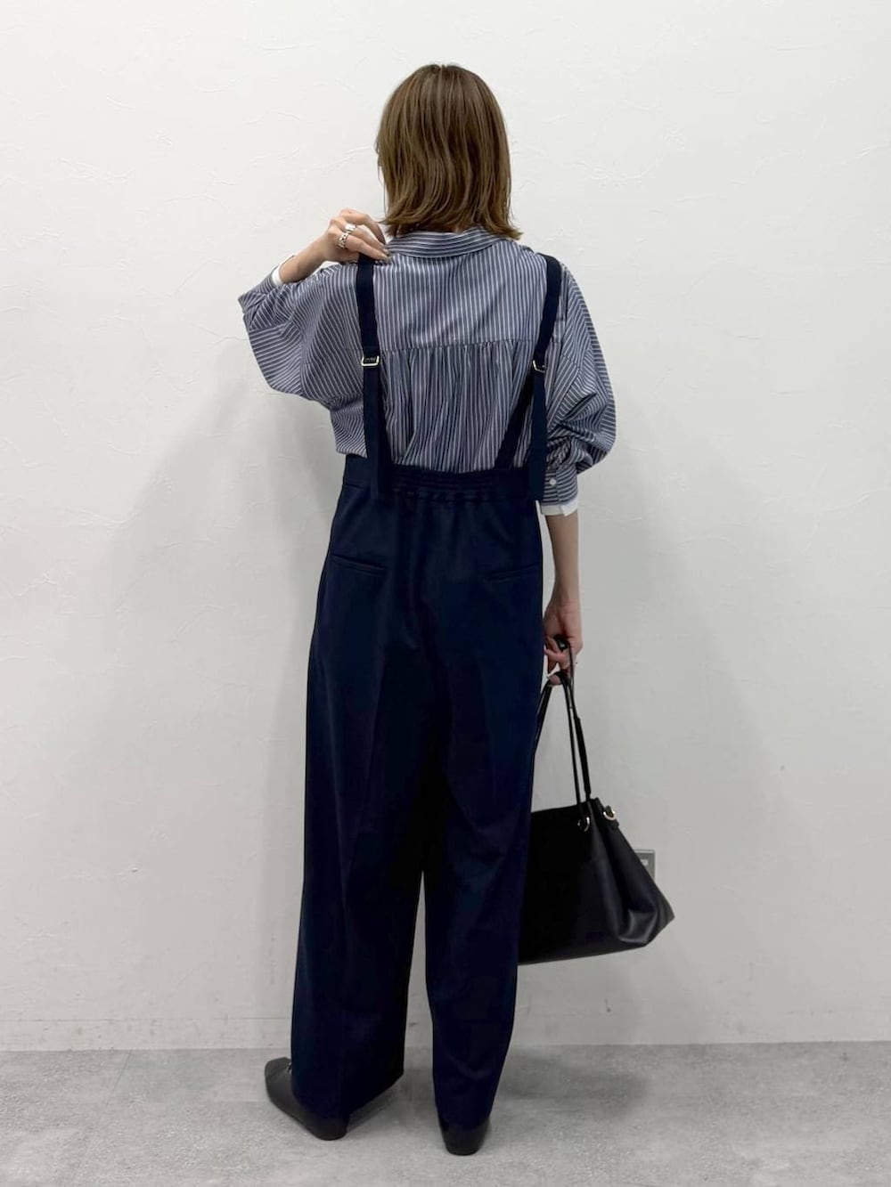 ブラック系のパンプス、ホワイト系のシャツ/ブラウス、グレー系のサロペット/オーバーオールを着用したレディースの春コーディネートの3枚目の写真