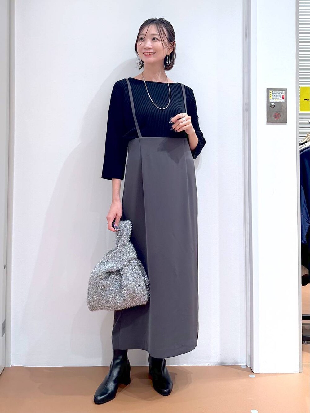 ブラック系のニット/セーター、グレー系のスカート、シルバー系のネックレスを着用したレディースの秋コーディネートの2枚目の写真