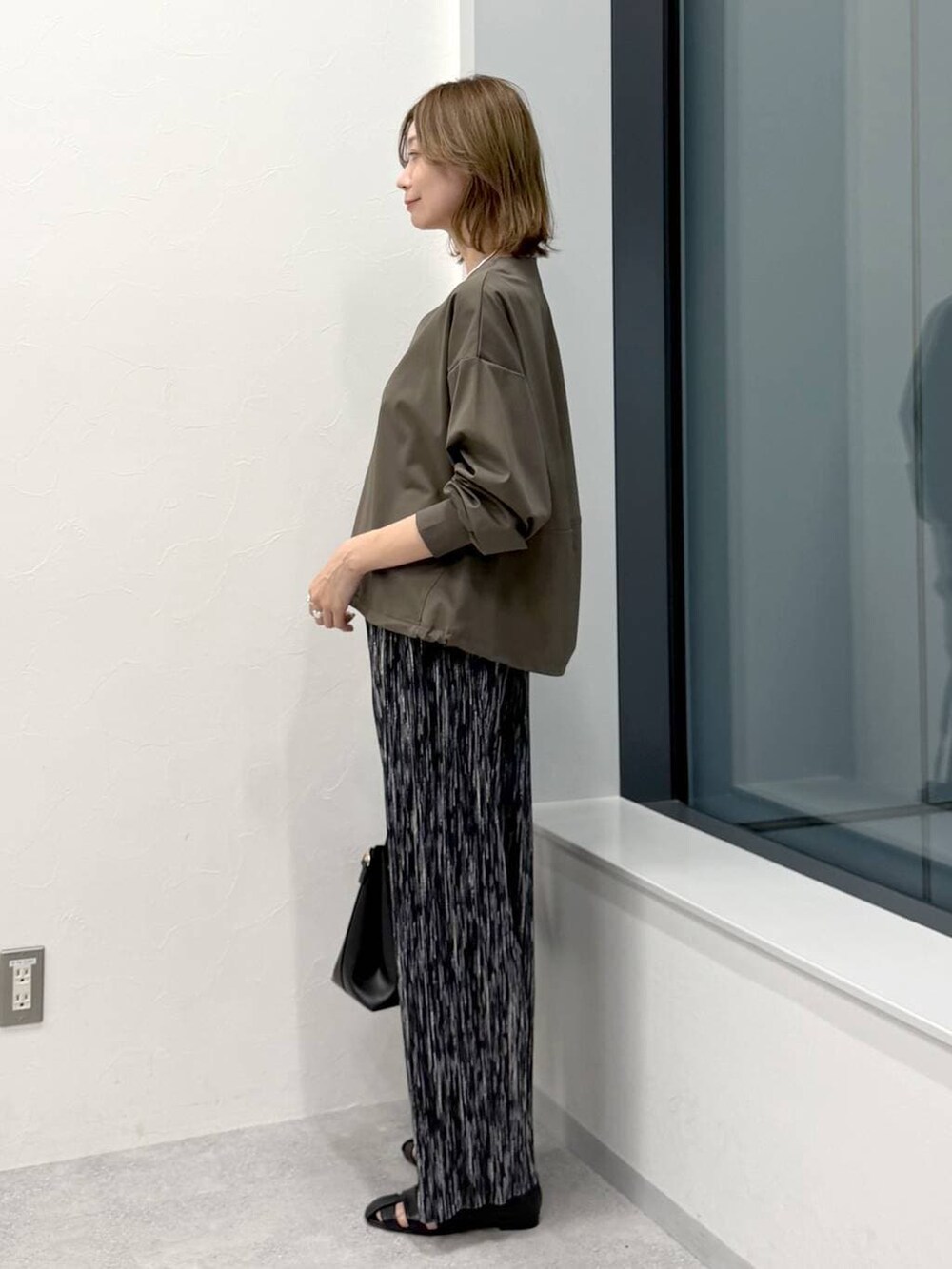 ブラック系のその他パンツ、ブラック系のトートバッグ、グリーン系のTシャツ/カットソーを着用したレディースの冬コーディネートの3枚目の写真