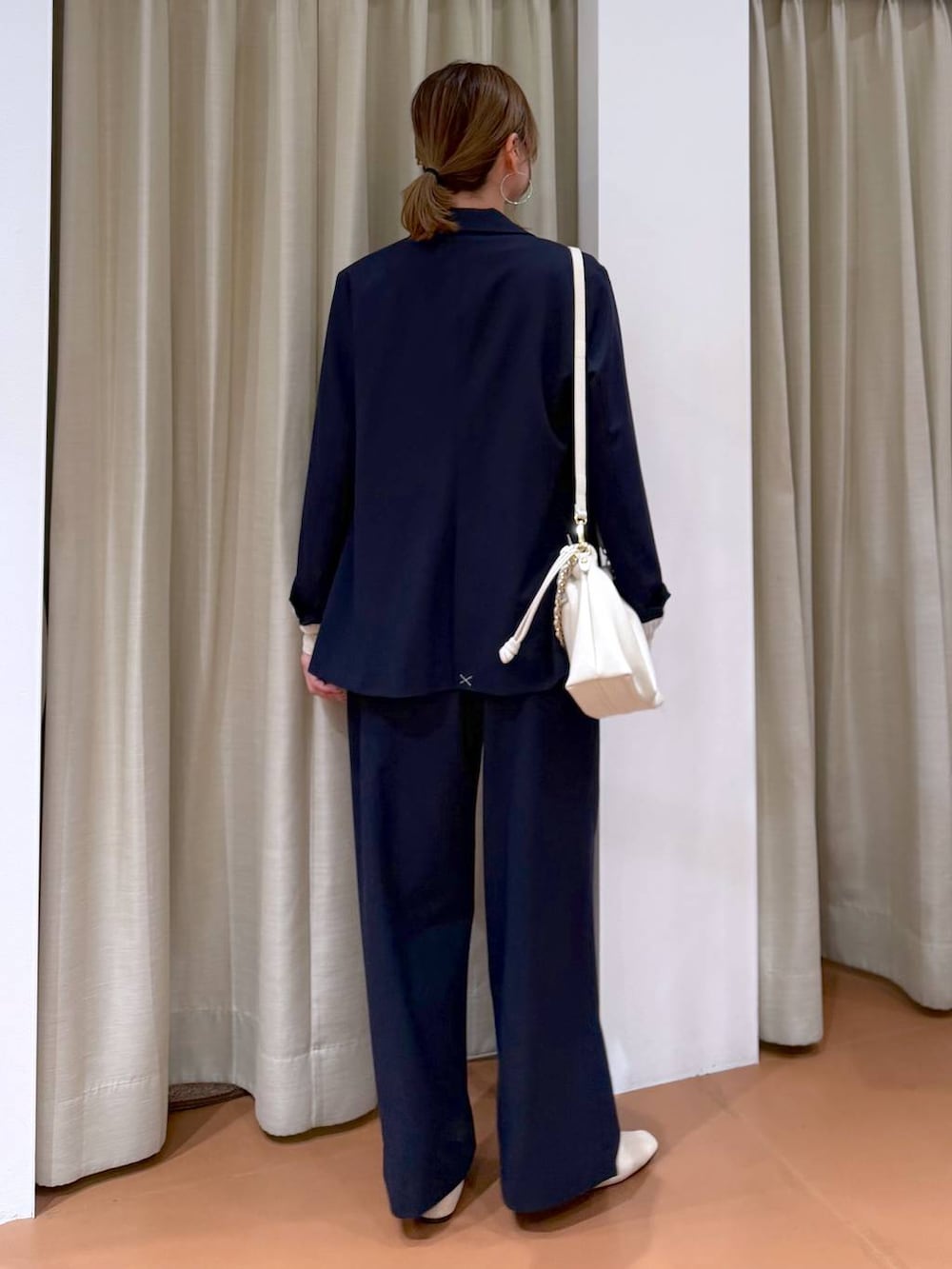 ホワイト系のハンドバッグ、ホワイト系のパンプス、ブルー系のその他パンツを着用したレディースの春コーディネートの4枚目の写真