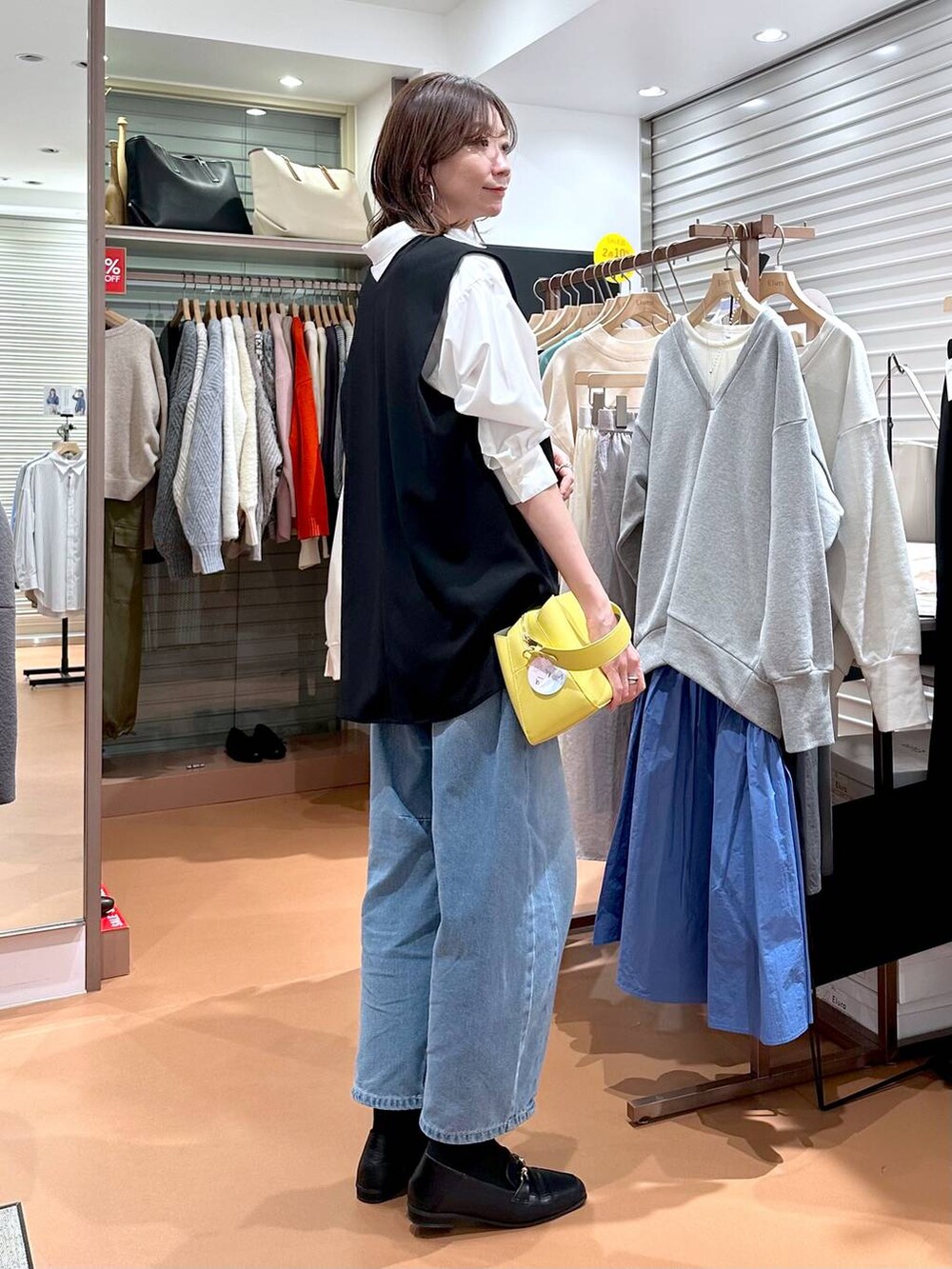 イエロー系のハンドバッグ、ホワイト系のシャツ/ブラウス、ブラック系のローファーを着用したレディースの冬コーディネートの5枚目の写真