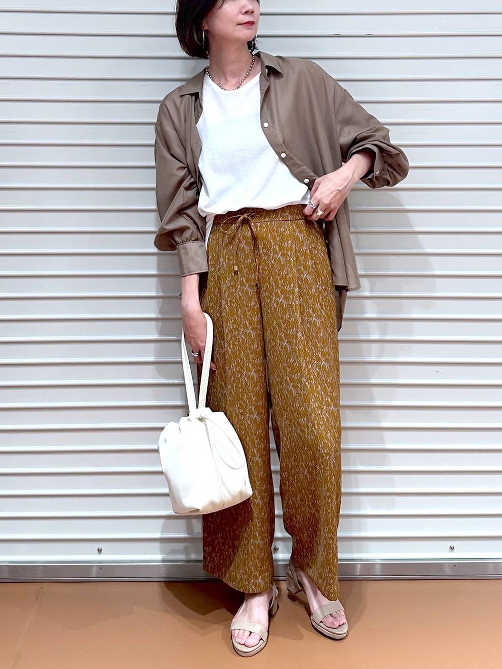 ベージュ系のサンダル、ブラウン系のその他パンツ、ホワイト系のTシャツ/カットソーを着用したレディースの秋コーディネートの5枚目の写真