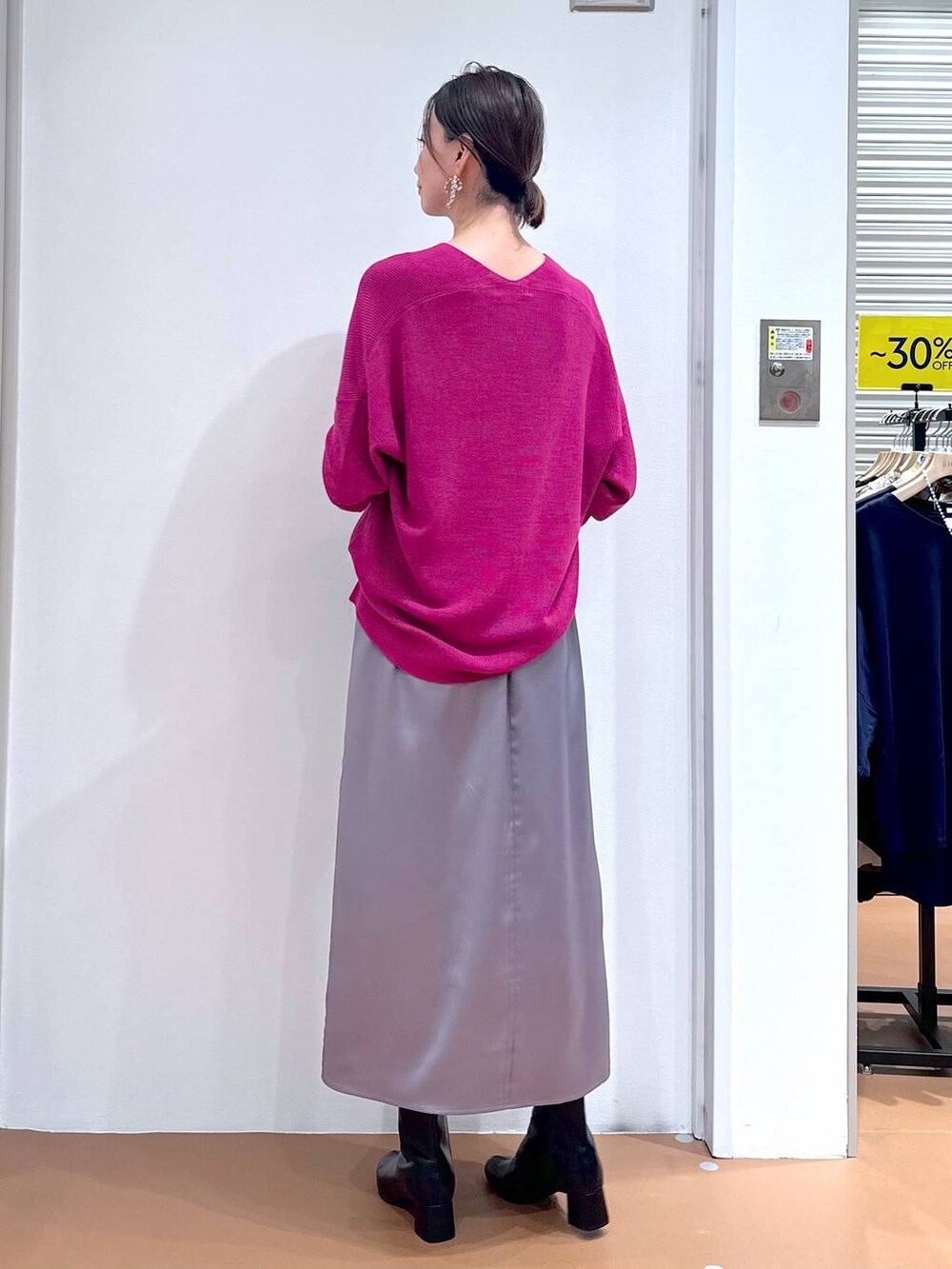 ピンク系のニット/セーター、グレー系のスカート、ブラック系のブーツを着用したレディースの秋コーディネートの4枚目の写真