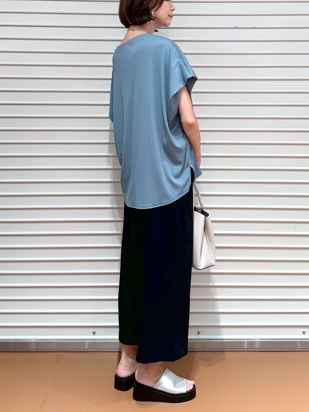 グリーン系のTシャツ/カットソー、シルバー系のサンダル、ブラック系のスカートを着用したレディースの秋コーディネートの6枚目の写真