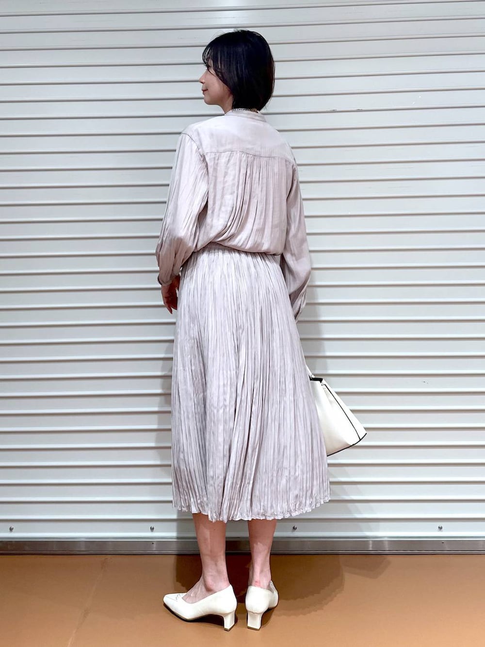 ホワイト系のショルダーバッグ、ピンク系のスカート、ホワイト系のパンプスを着用したレディースの冬コーディネートの3枚目の写真