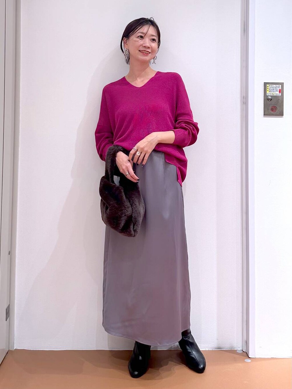 ピンク系のニット/セーター、グレー系のスカート、ブラック系のブーツを着用したレディースの秋コーディネートの2枚目の写真