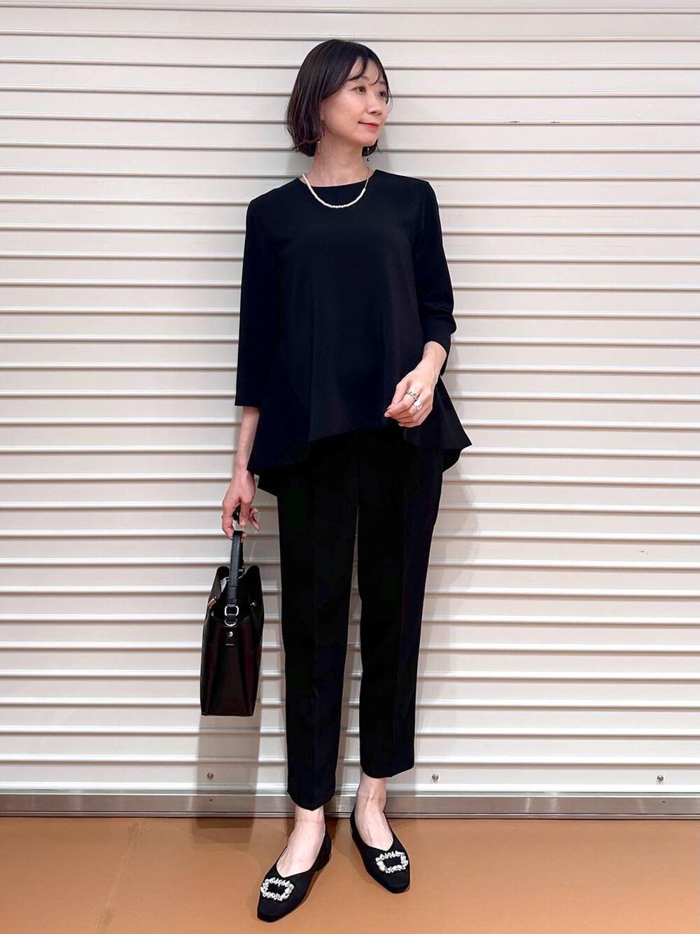 ブラック系のその他パンツ、ブラック系のシャツ/ブラウス、ブラック系のハンドバッグを着用したレディースの春コーディネートの2枚目の写真