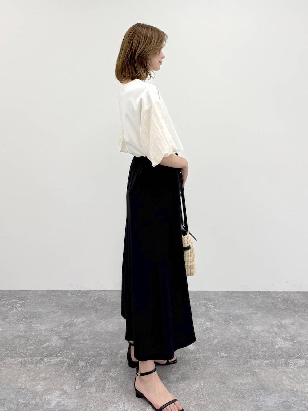 ホワイト系のTシャツ/カットソー、ブラック系のスカート、ゴールド系のネックレスを着用したレディースの春コーディネートの5枚目の写真