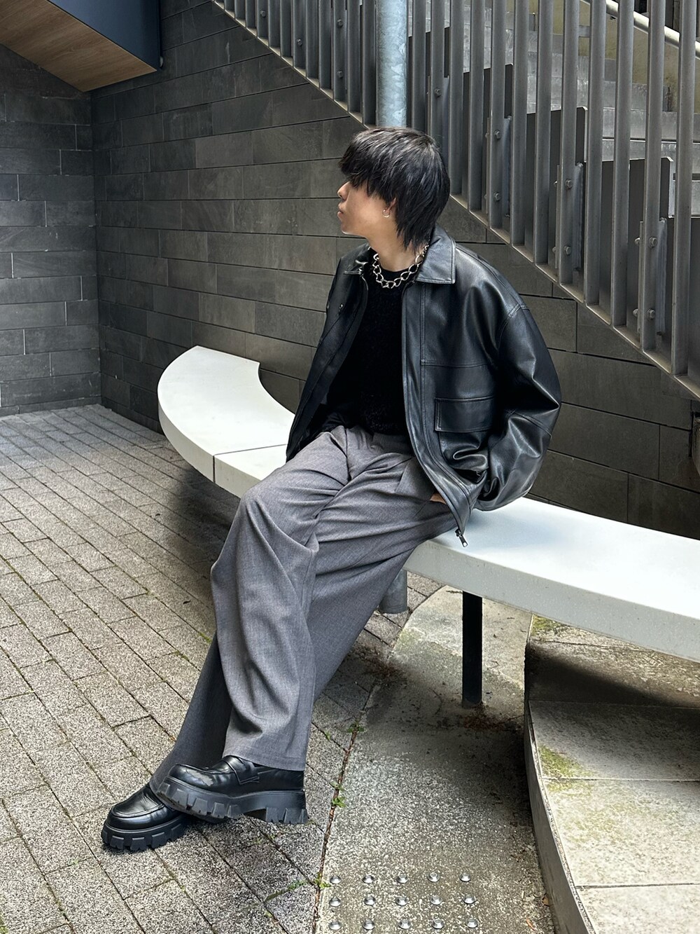 ブラック系のブルゾン、ブラック系のTシャツ/カットソー、グレー系のスラックスを着用したメンズの冬コーディネートの2枚目の写真