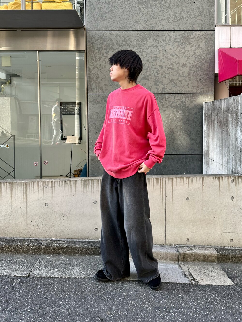 レッド系のスウェット、ブラック系のデニムパンツ、ブラック系のモカシン/デッキシューズを着用したメンズの秋コーディネートの2枚目の写真