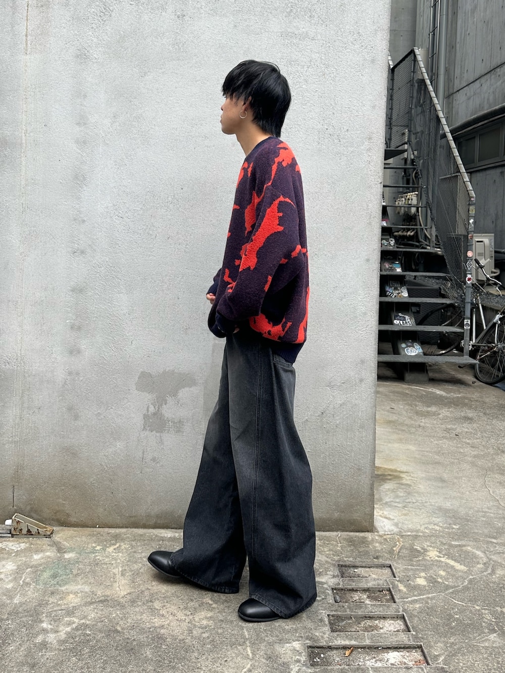 ブルー系のニット/セーター、ブラック系のデニムパンツ、ブラック系のブーツを着用したメンズの秋コーディネートの2枚目の写真