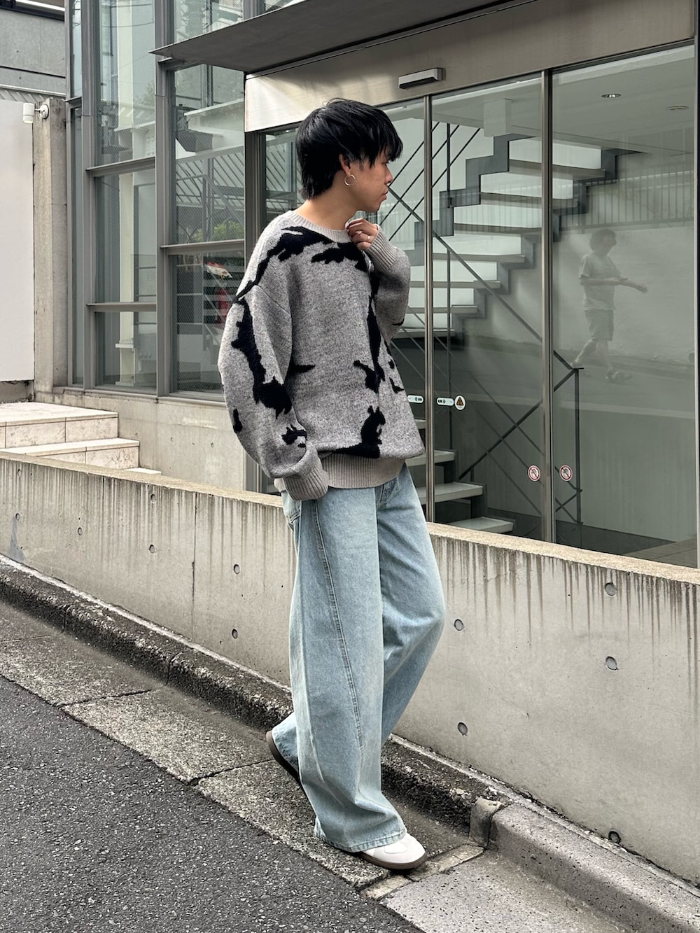 グレー系のニット/セーター、ブルー系のデニムパンツ、ホワイト系のスニーカーを着用したメンズの秋コーディネートの2枚目の写真