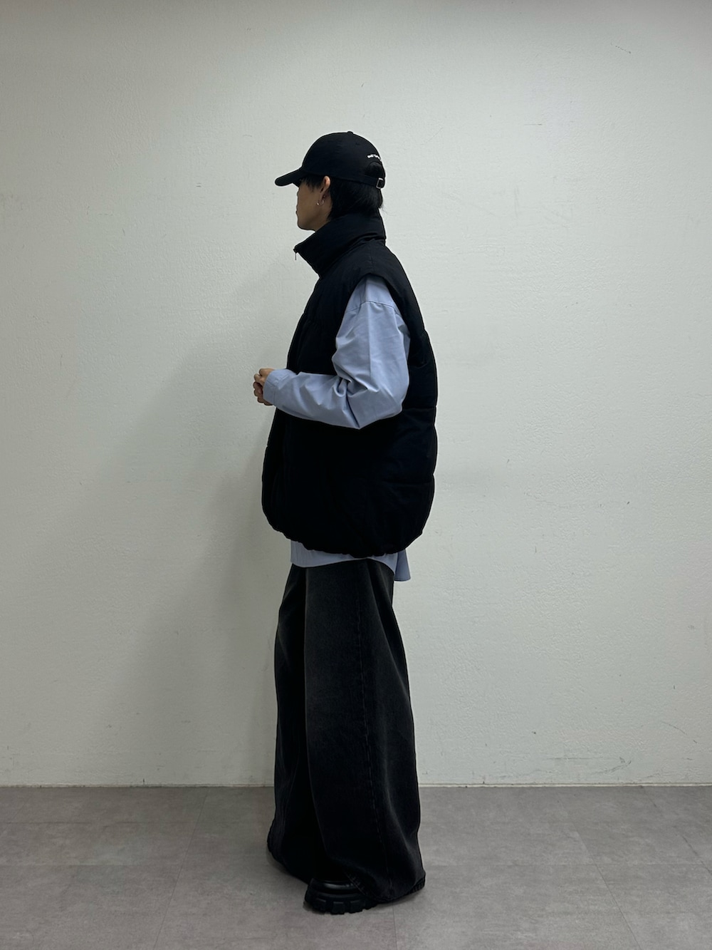 ブラック系のダウンベスト、ブラック系のデニムパンツ、ブルー系のキャップを着用したメンズの夏コーディネートの2枚目の写真