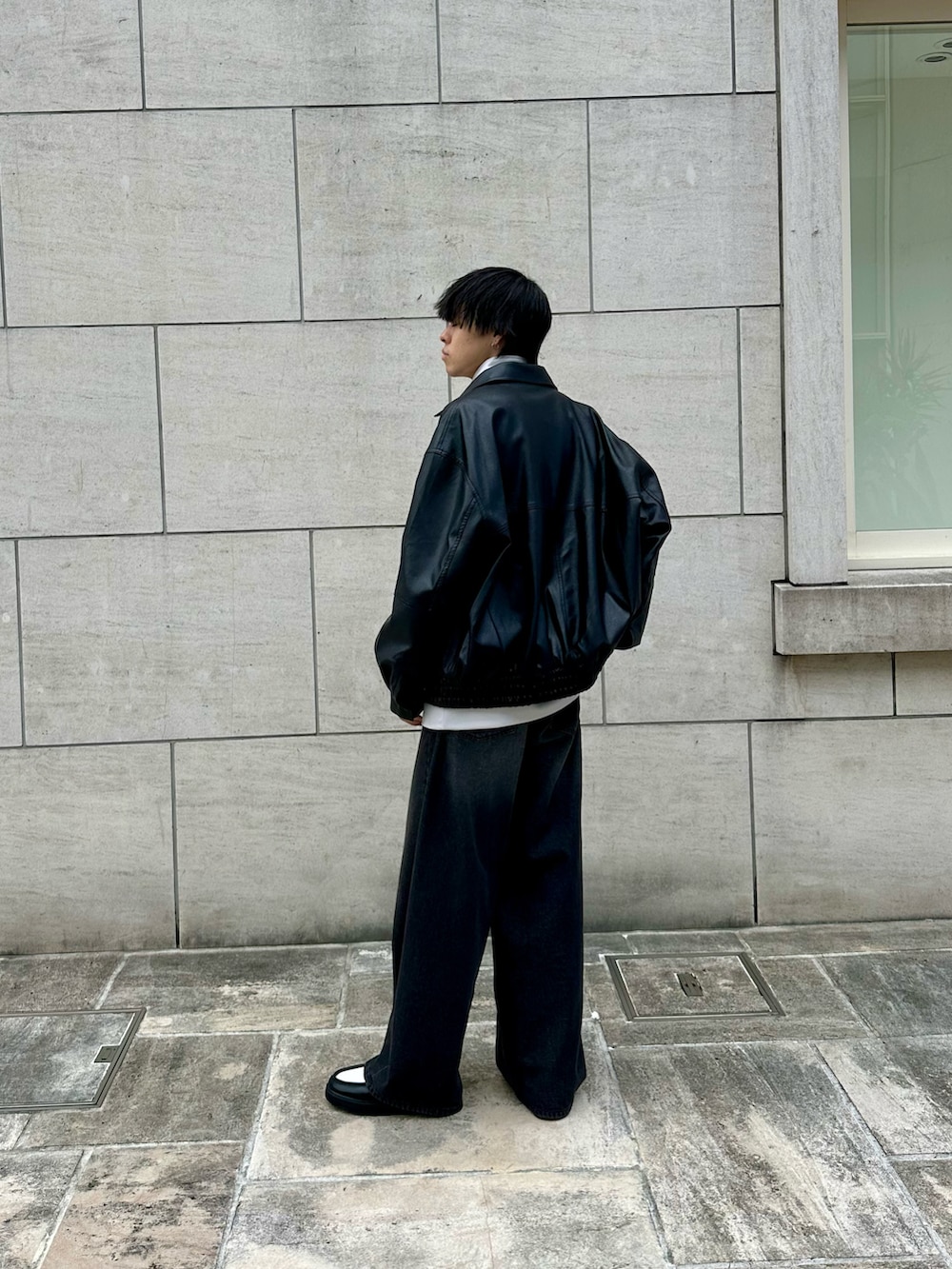 ブラック系のブルゾン、グレー系のTシャツ/カットソー、ブラック系のデニムパンツを着用したメンズの秋コーディネートの2枚目の写真