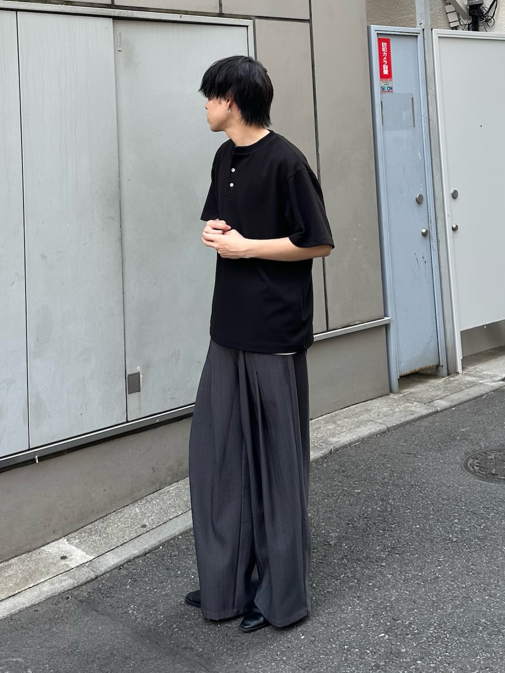 ブラック系のTシャツ/カットソー、グレー系のスラックスを着用したメンズの春コーディネートの2枚目の写真