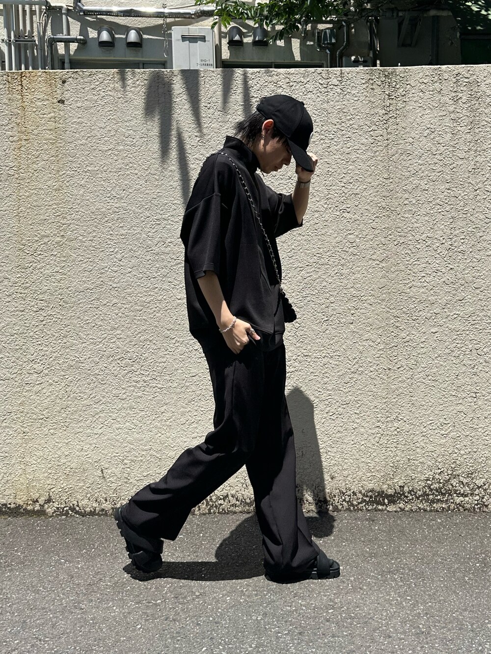 ブラック系のスラックス、ブラック系のTシャツ/カットソー、ブラック系のショルダーバッグを着用したメンズの夏コーディネートの3枚目の写真