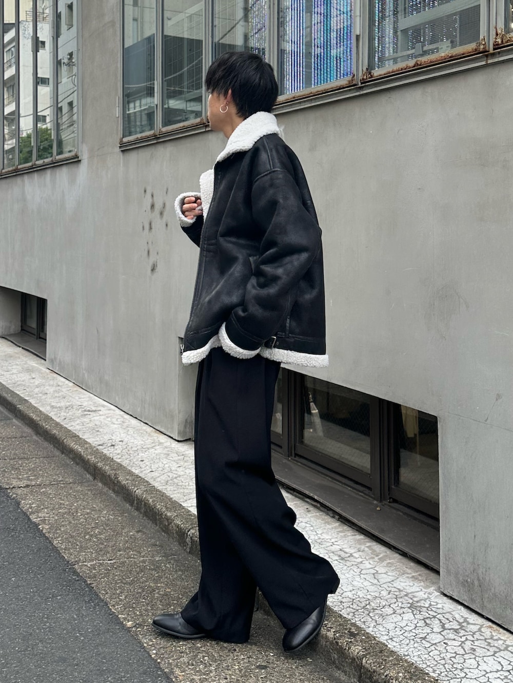 ブラック系のムートンコート、ブラック系のスラックス、ブラック系のベルトを着用したメンズの秋コーディネートの2枚目の写真