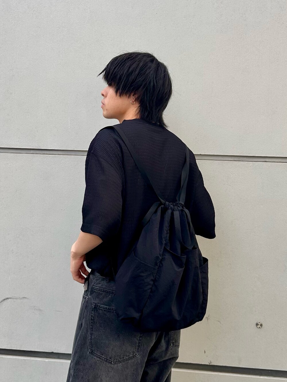 ブラック系のTシャツ/カットソー、ブラック系のバックパック/リュック、ブラック系のデニムパンツを着用したメンズの春コーディネートの5枚目の写真