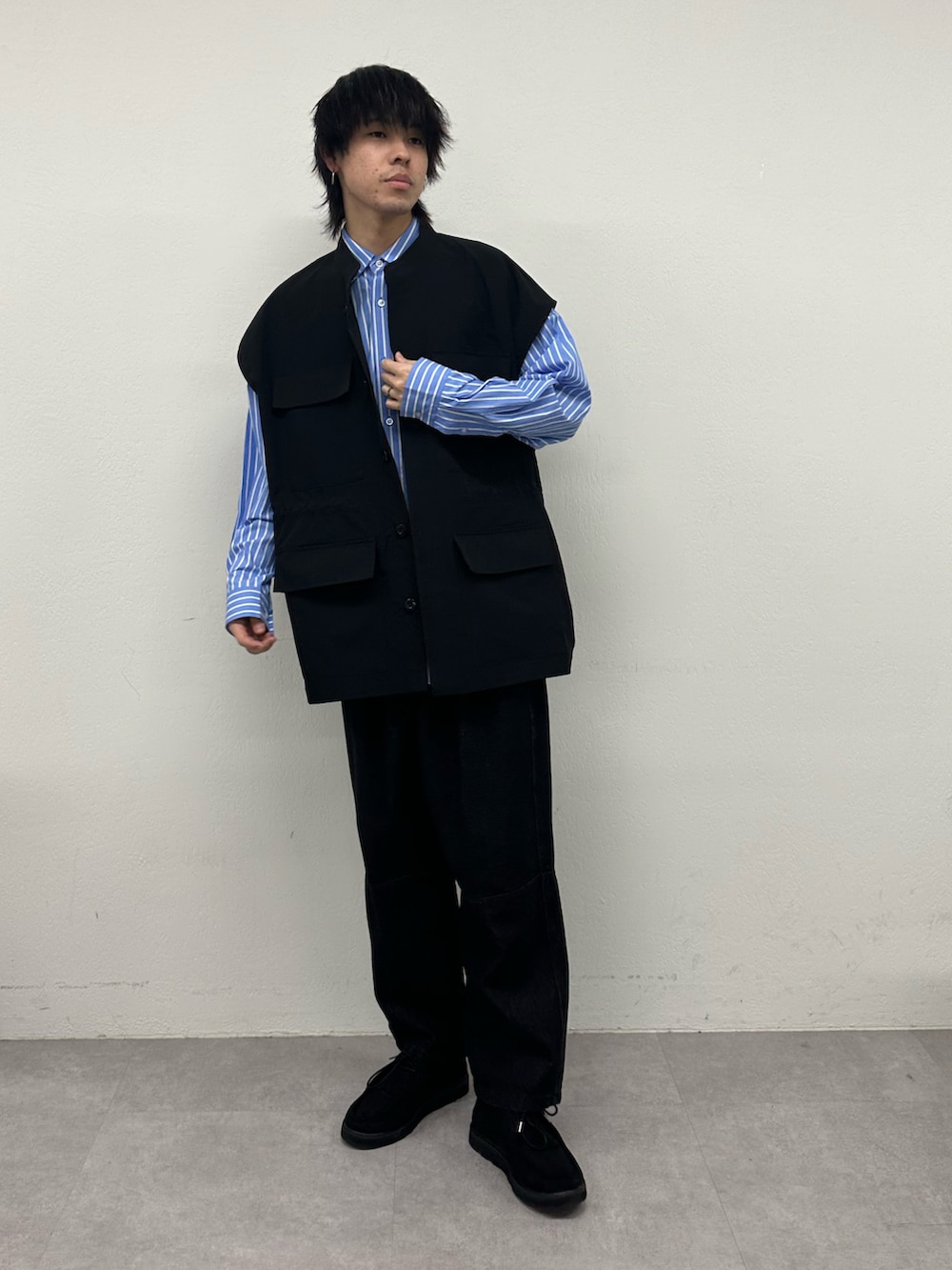 ブラック系のベスト、ブルー系のシャツ/ブラウス、ブラック系のデニムパンツを着用したメンズの春コーディネートの2枚目の写真