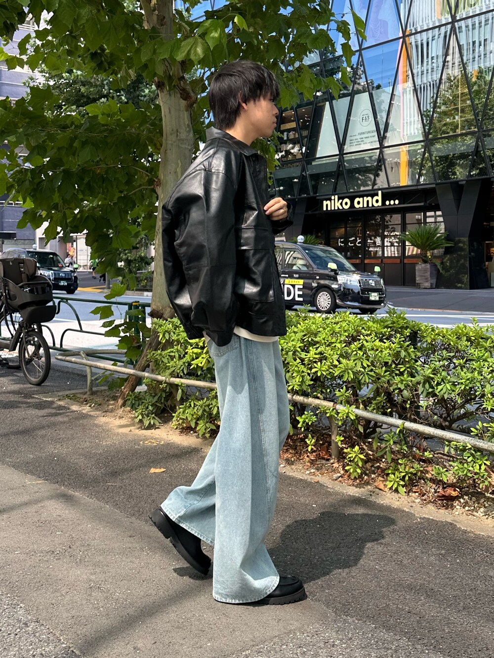 ブラック系のブルゾン、ホワイト系のスウェット、ブルー系のデニムパンツを着用したメンズの秋コーディネートの4枚目の写真