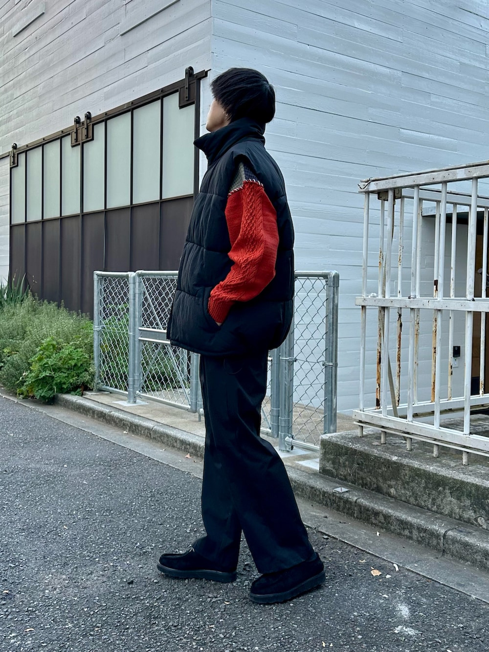 ブラック系のダウンベスト、オレンジ系のニット/セーター、ブラック系のその他パンツを着用したメンズの冬コーディネートの2枚目の写真