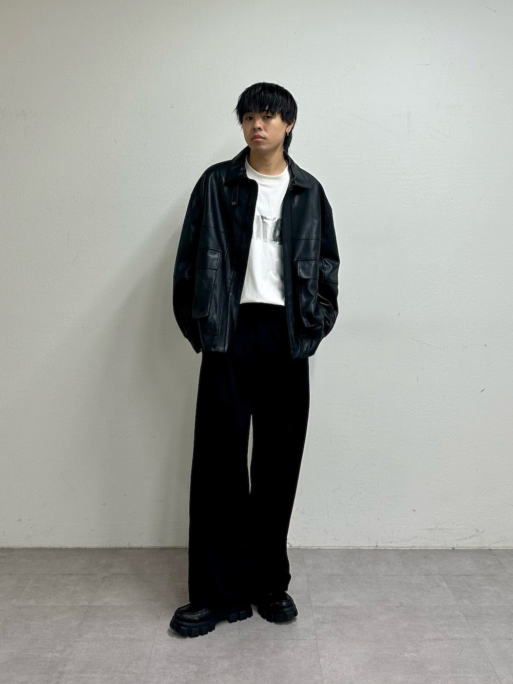 ブラック系のブルゾン、ホワイト系のTシャツ/カットソー、ブラック系のスラックスを着用したメンズの夏コーディネートの4枚目の写真