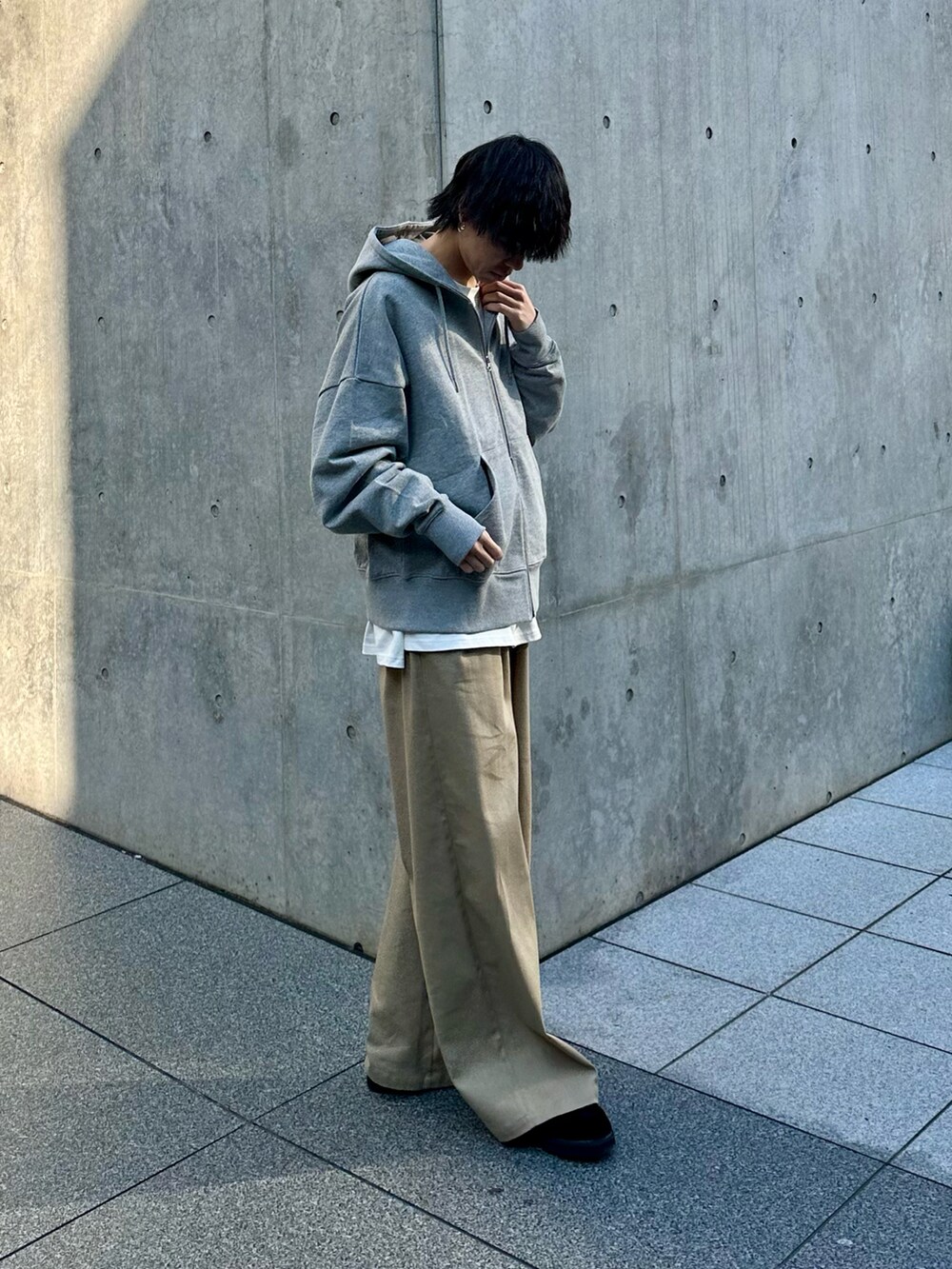 グレー系のパーカー、ベージュ系のスラックスを着用したメンズの冬コーディネートの2枚目の写真