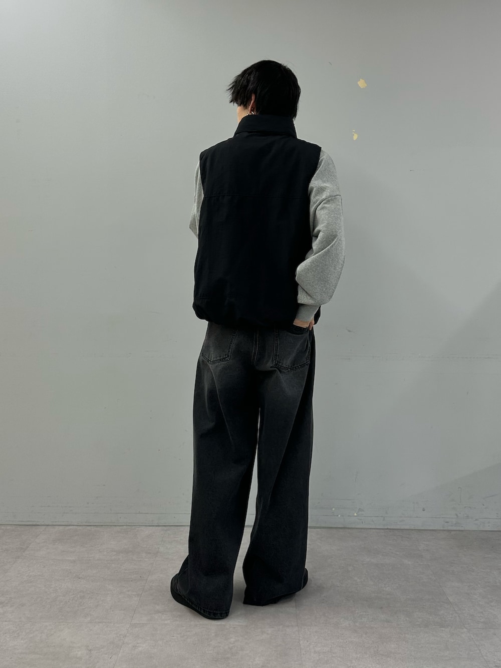 ブラック系のベスト、グレー系のスウェット、ブラック系のデニムパンツを着用したメンズの冬コーディネートの3枚目の写真