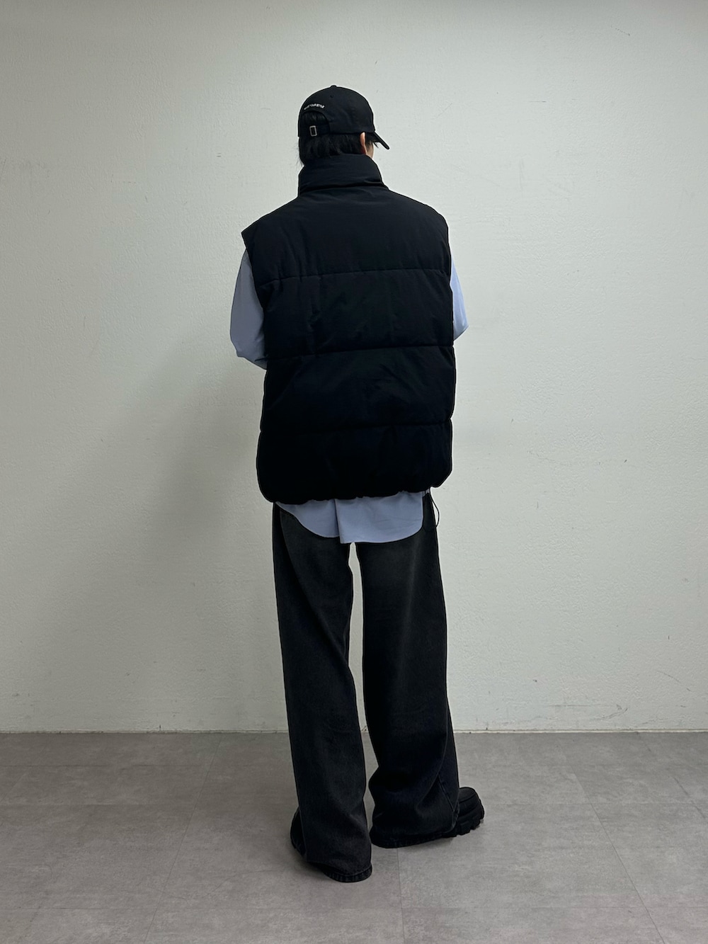 ブラック系のダウンベスト、ブラック系のデニムパンツ、ブルー系のキャップを着用したメンズの夏コーディネートの3枚目の写真