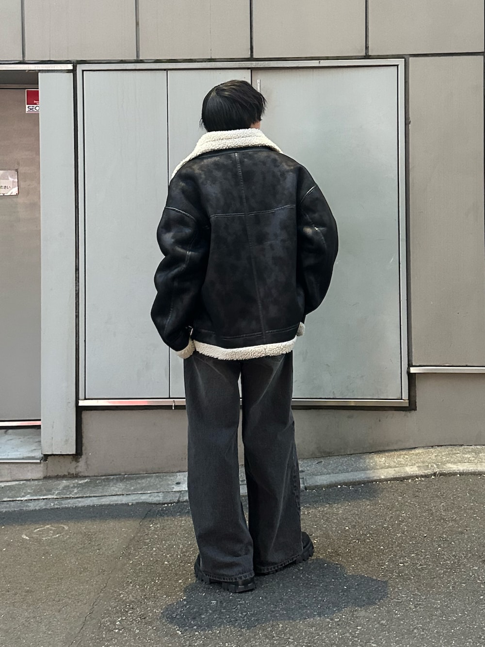 ブラック系のムートンコート、ブラック系のニット/セーター、ブラック系のデニムパンツを着用したメンズの冬コーディネートの3枚目の写真