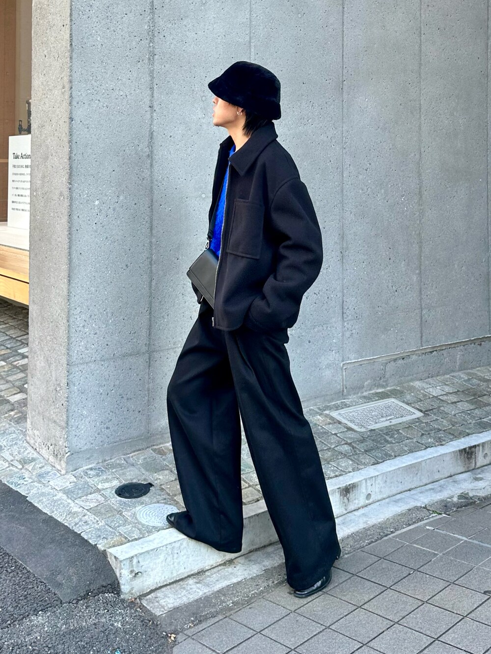 ブラック系のブルゾン、ブルー系のニット/セーター、ブラック系のスラックスを着用したメンズの秋コーディネートの4枚目の写真