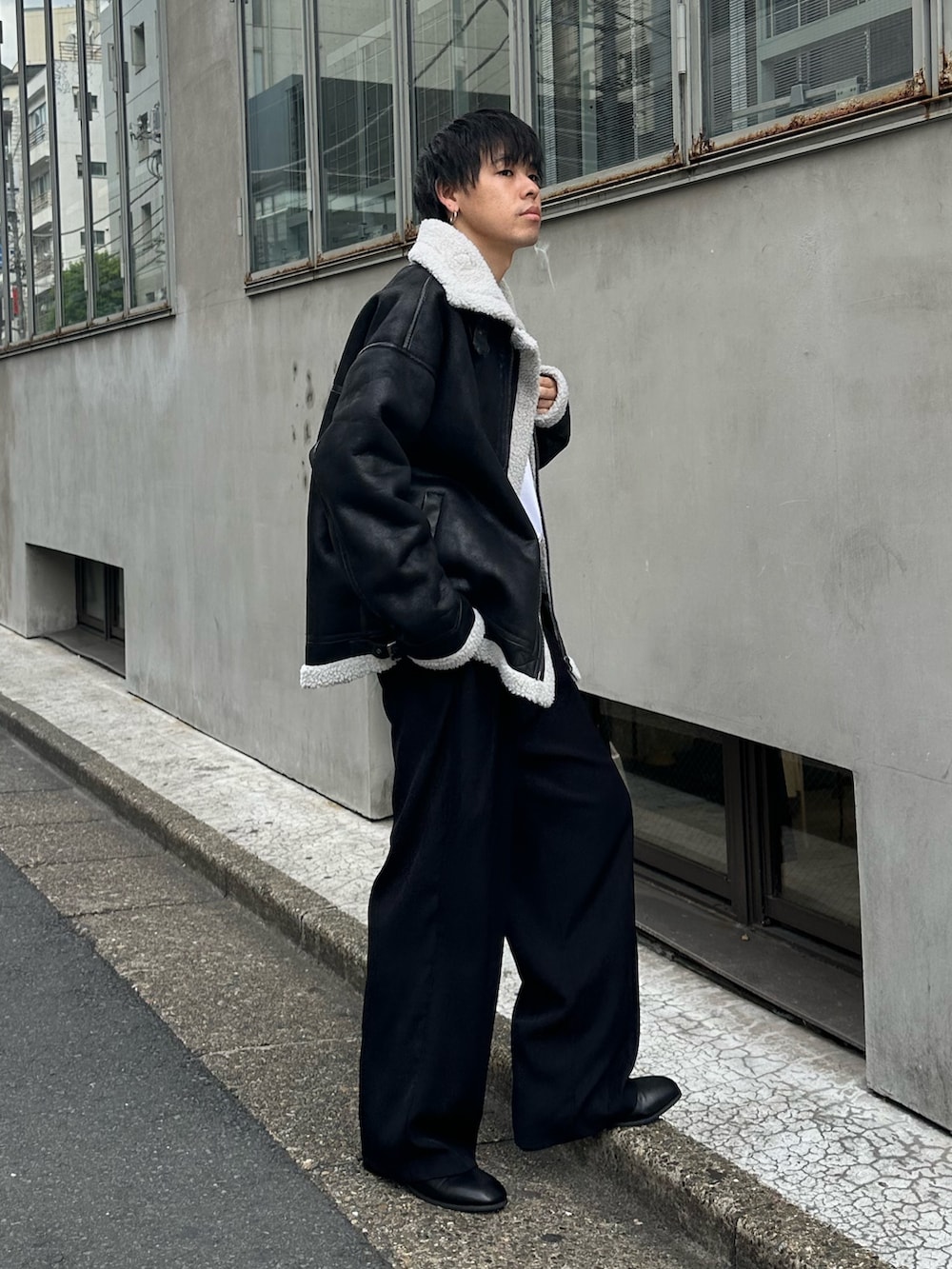 ブラック系のムートンコート、ブラック系のスラックス、ブラック系のベルトを着用したメンズの秋コーディネートの3枚目の写真