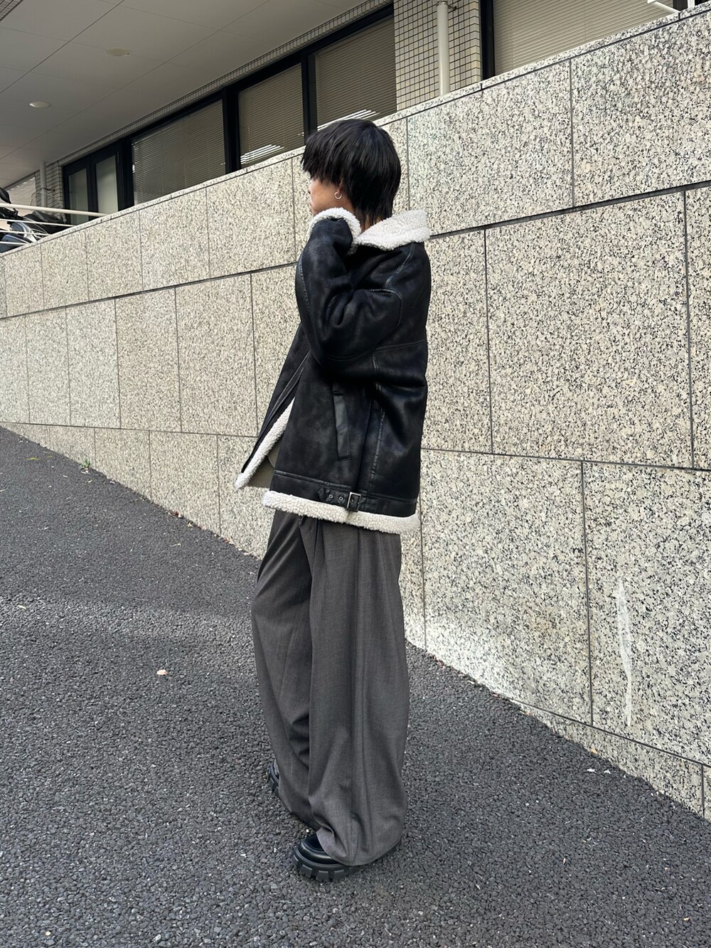ブラック系のムートンコート、ブラック系のTシャツ/カットソー、グレー系のスラックスを着用したメンズの冬コーディネートの2枚目の写真
