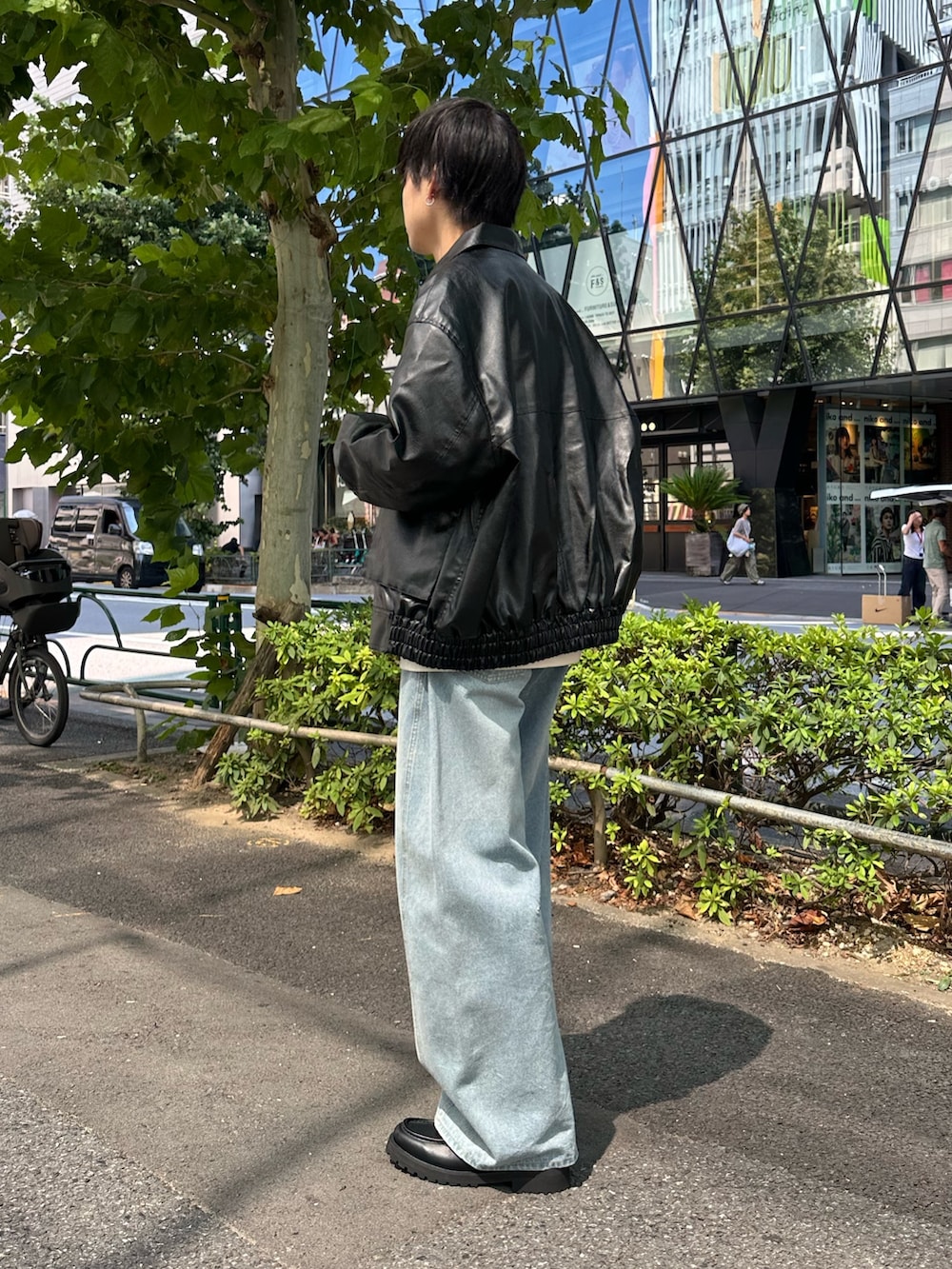 ブラック系のブルゾン、ホワイト系のスウェット、ブルー系のデニムパンツを着用したメンズの秋コーディネートの2枚目の写真