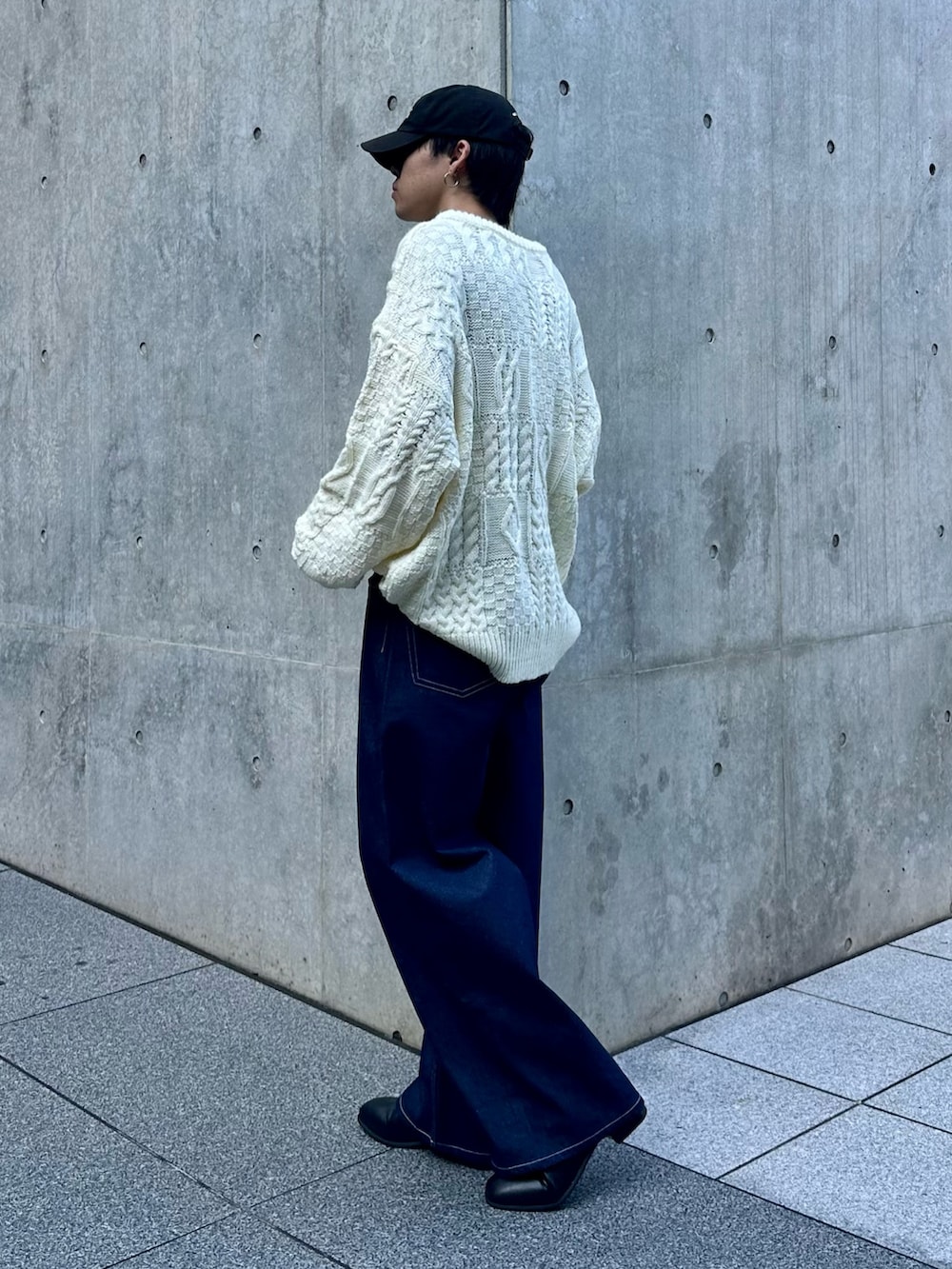 ホワイト系のニット/セーター、ブルー系のデニムパンツ、ブラック系のキャップを着用したメンズの秋コーディネートの2枚目の写真