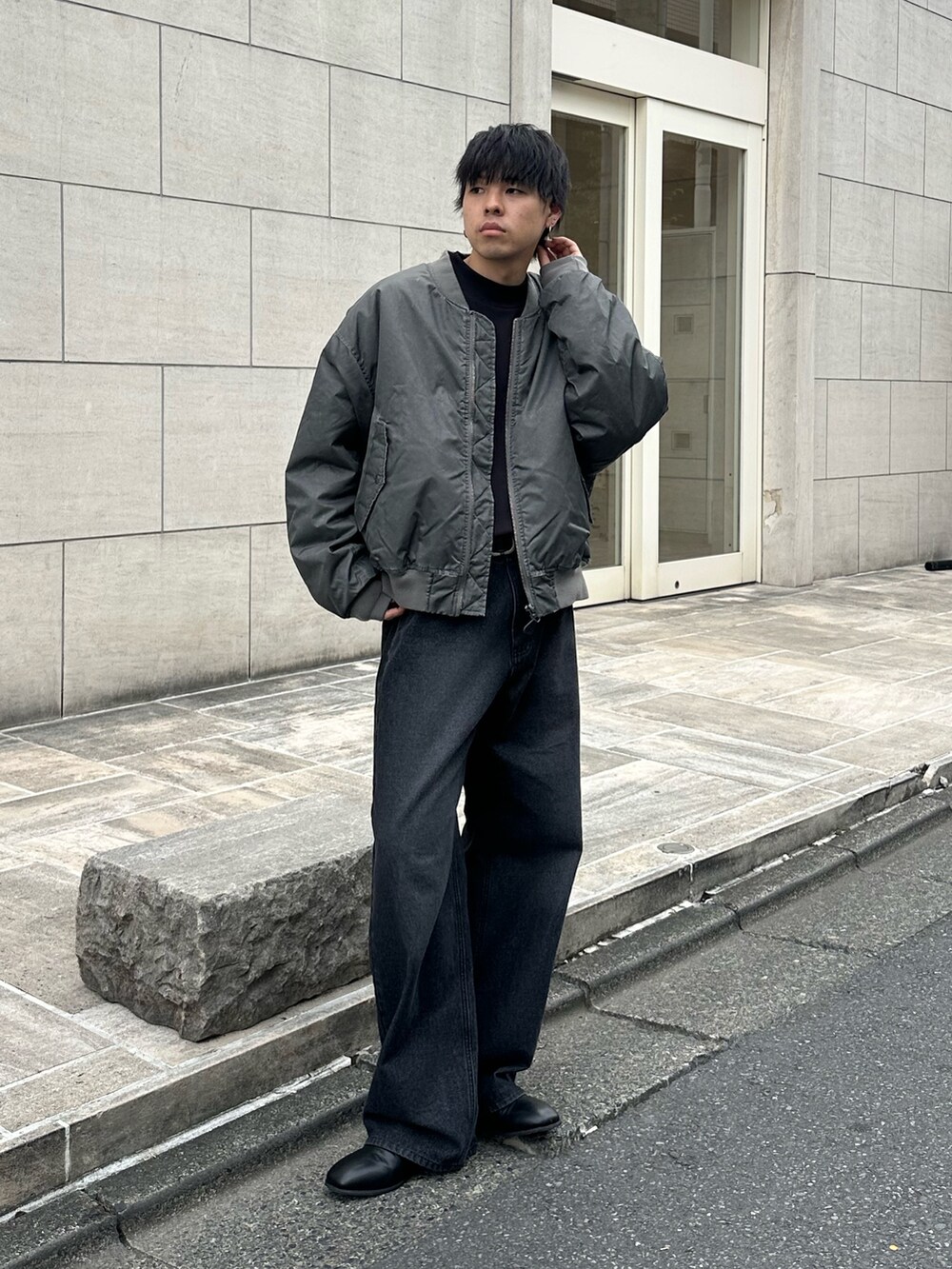 グレー系のブルゾン、ブラック系のTシャツ/カットソー、ブラック系のデニムパンツを着用したメンズの秋コーディネートの5枚目の写真