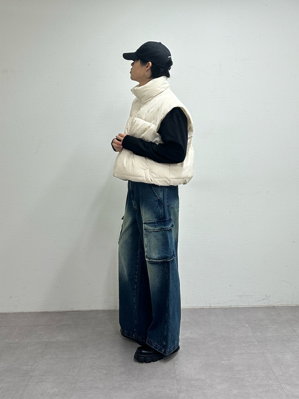 ホワイト系のダウンベスト、ブルー系のデニムパンツ、ブルー系のキャップを着用したメンズの夏コーディネートの2枚目の写真